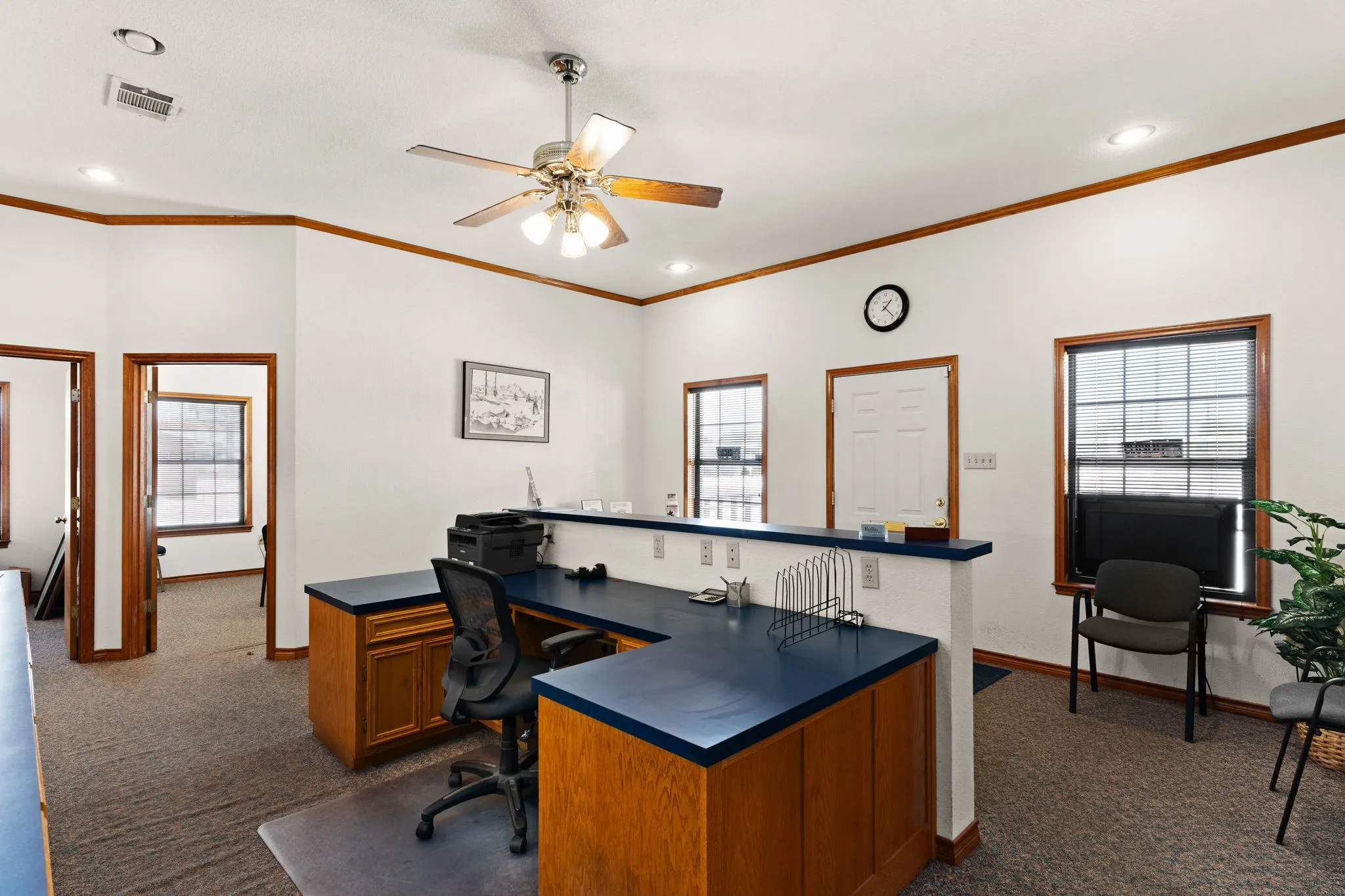 Office space featuring dark carpet, plenty of natural light, a ceiling fan, ornamental molding, and recessed lighting