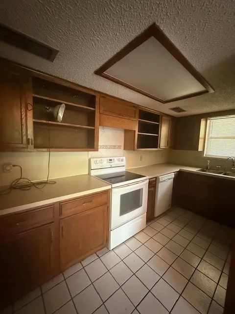 Kitchen featuring white appliances, open shelves, a textured ceiling, light tile patterned floors, and light countertops