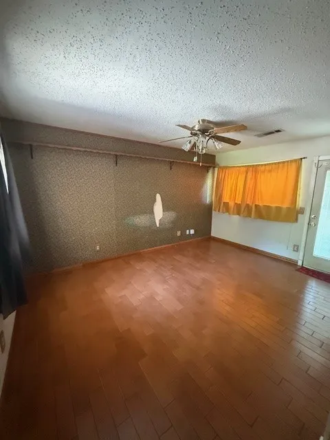 Spare room with a ceiling fan, wood finished floors, and a textured ceiling