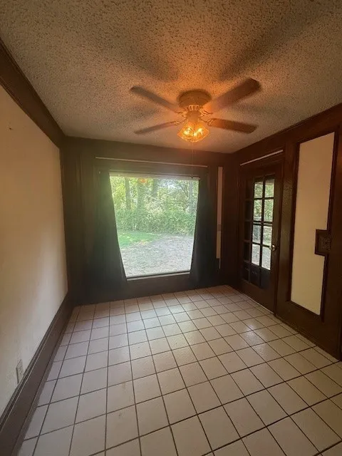Spare room featuring a textured ceiling, ceiling fan, and light tile patterned floors