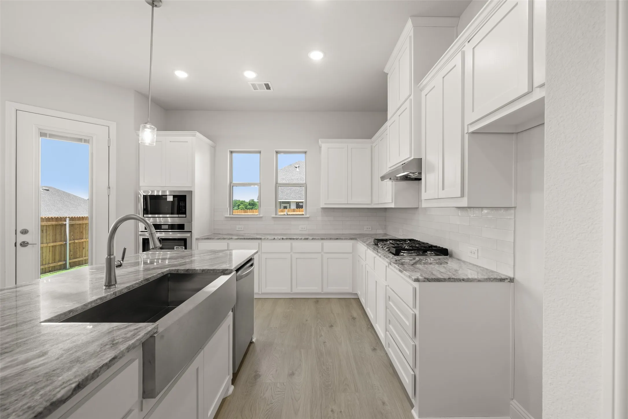 Kitchen featuring stainless steel appliances, backsplash, white cabinetry, and recessed lighting