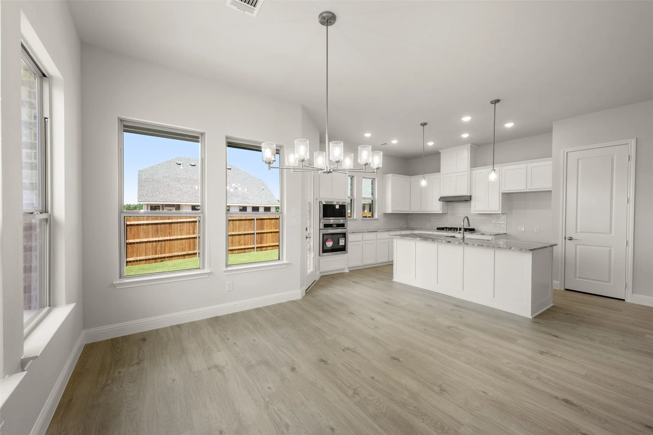 Kitchen featuring light wood-style floors, white cabinets, recessed lighting, backsplash, and pendant lighting