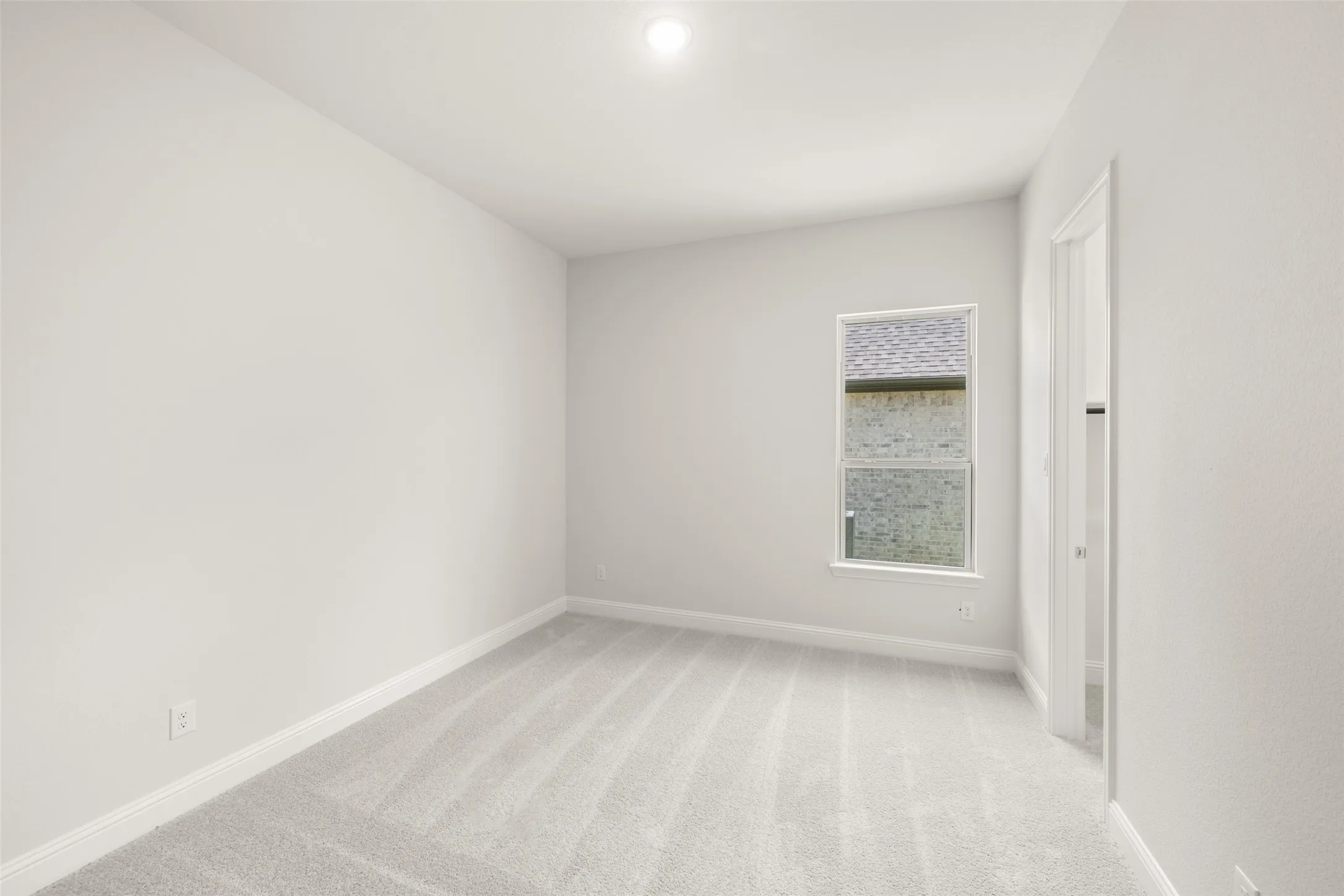 Empty room with baseboards and light colored carpet
