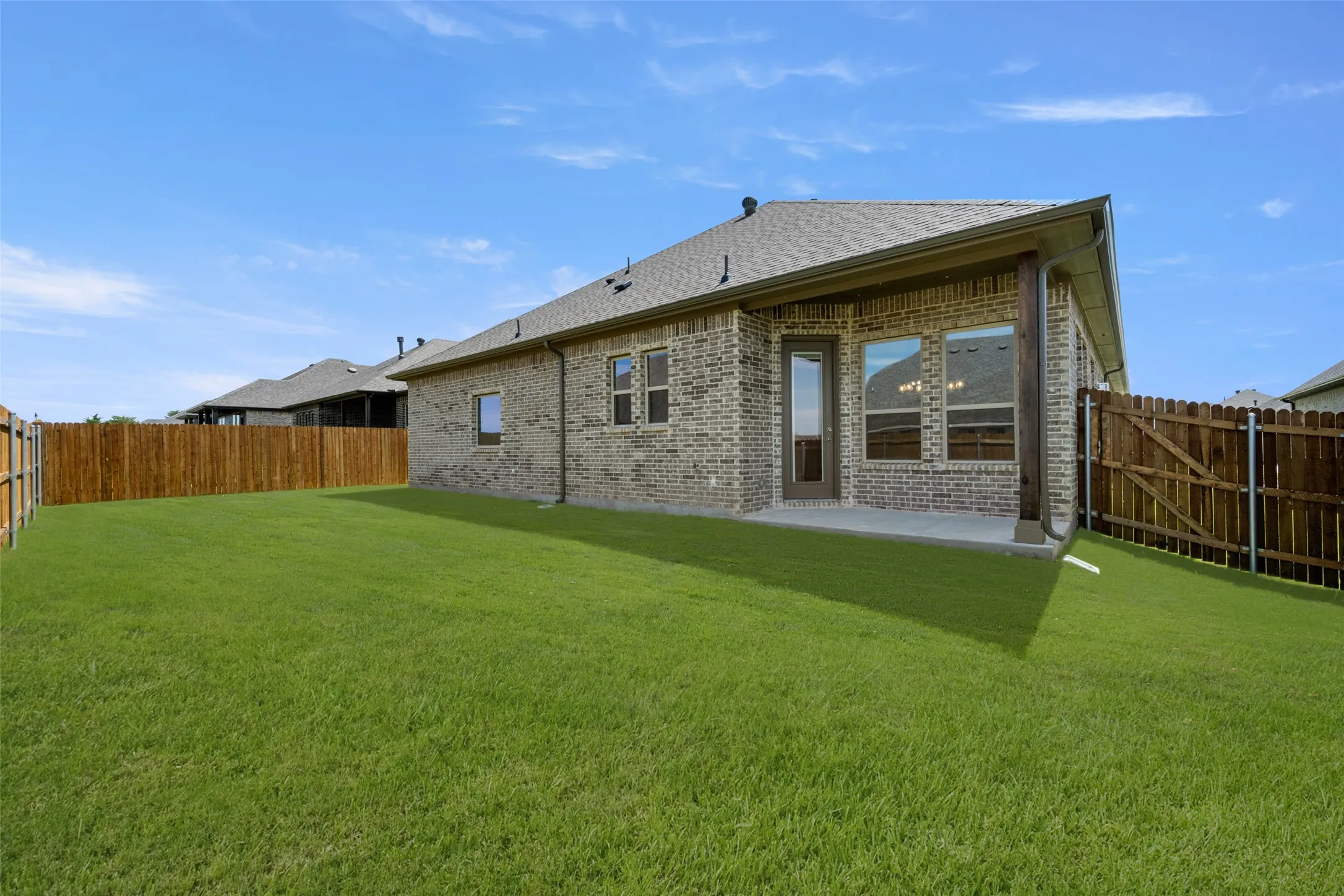 Back of house featuring brick siding, a fenced backyard, a patio, and a shingled roof