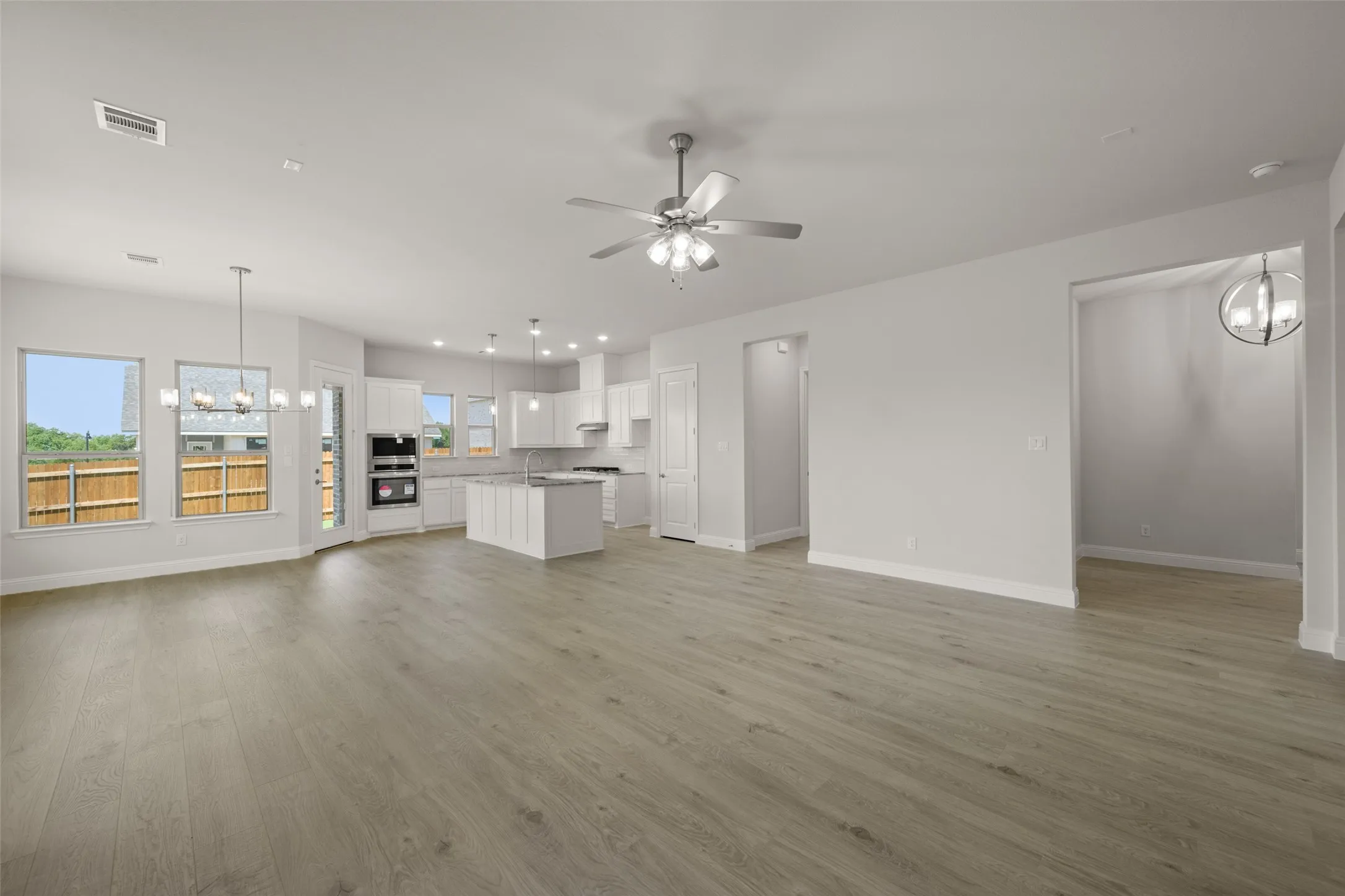 Unfurnished living room with a chandelier, a ceiling fan, and light wood-style flooring