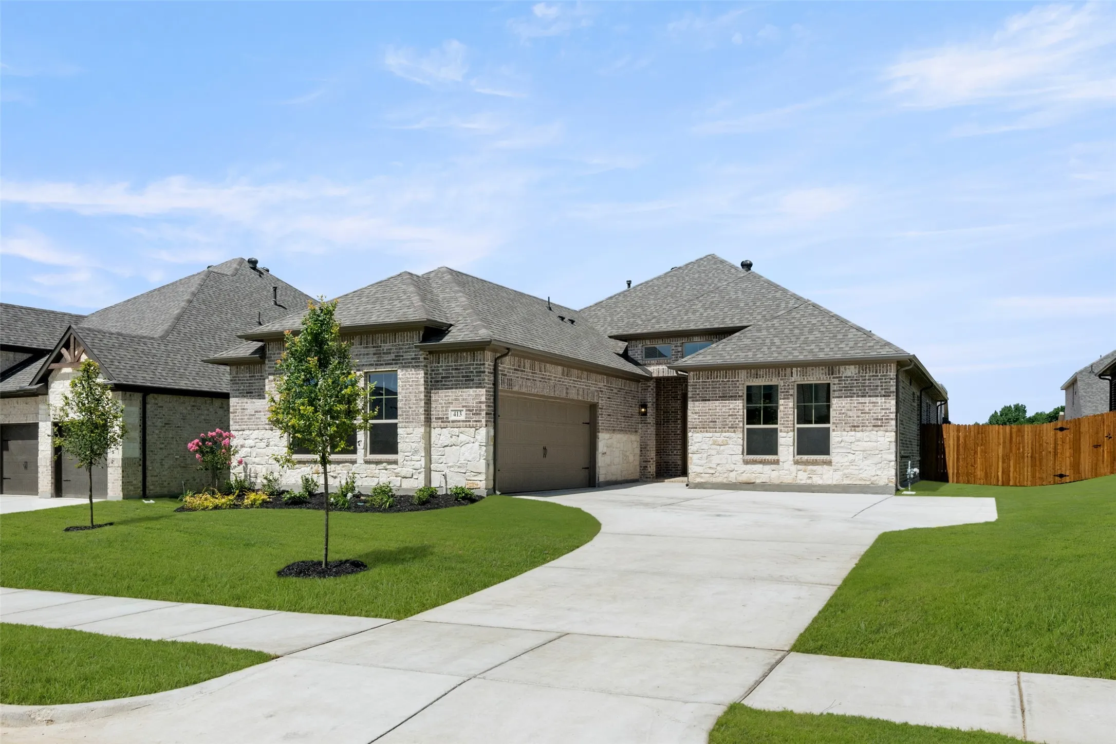 French country inspired facade with roof with shingles, brick siding, driveway, and a garage