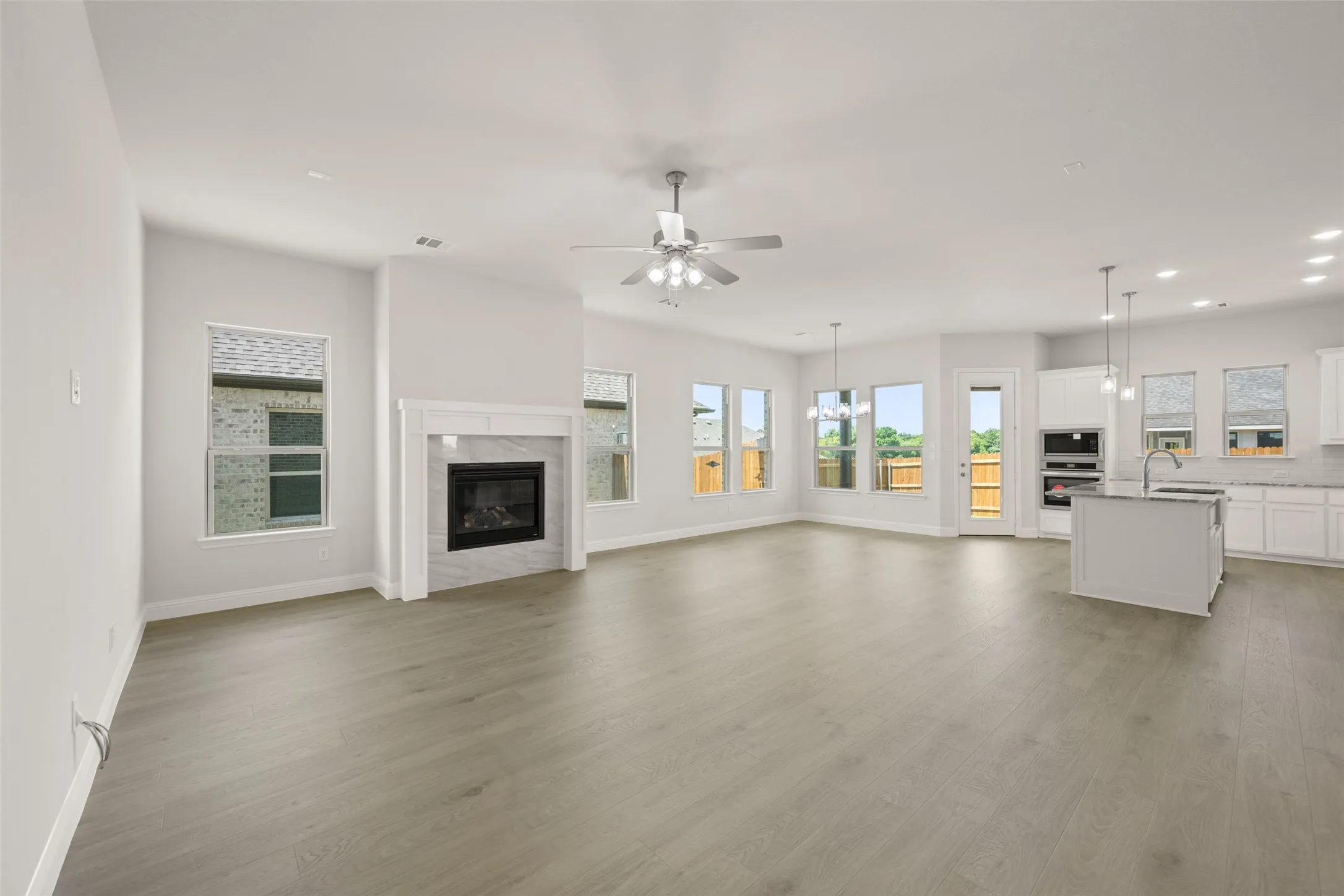 Unfurnished living room featuring recessed lighting, ceiling fan, a high end fireplace, and light wood-style floors