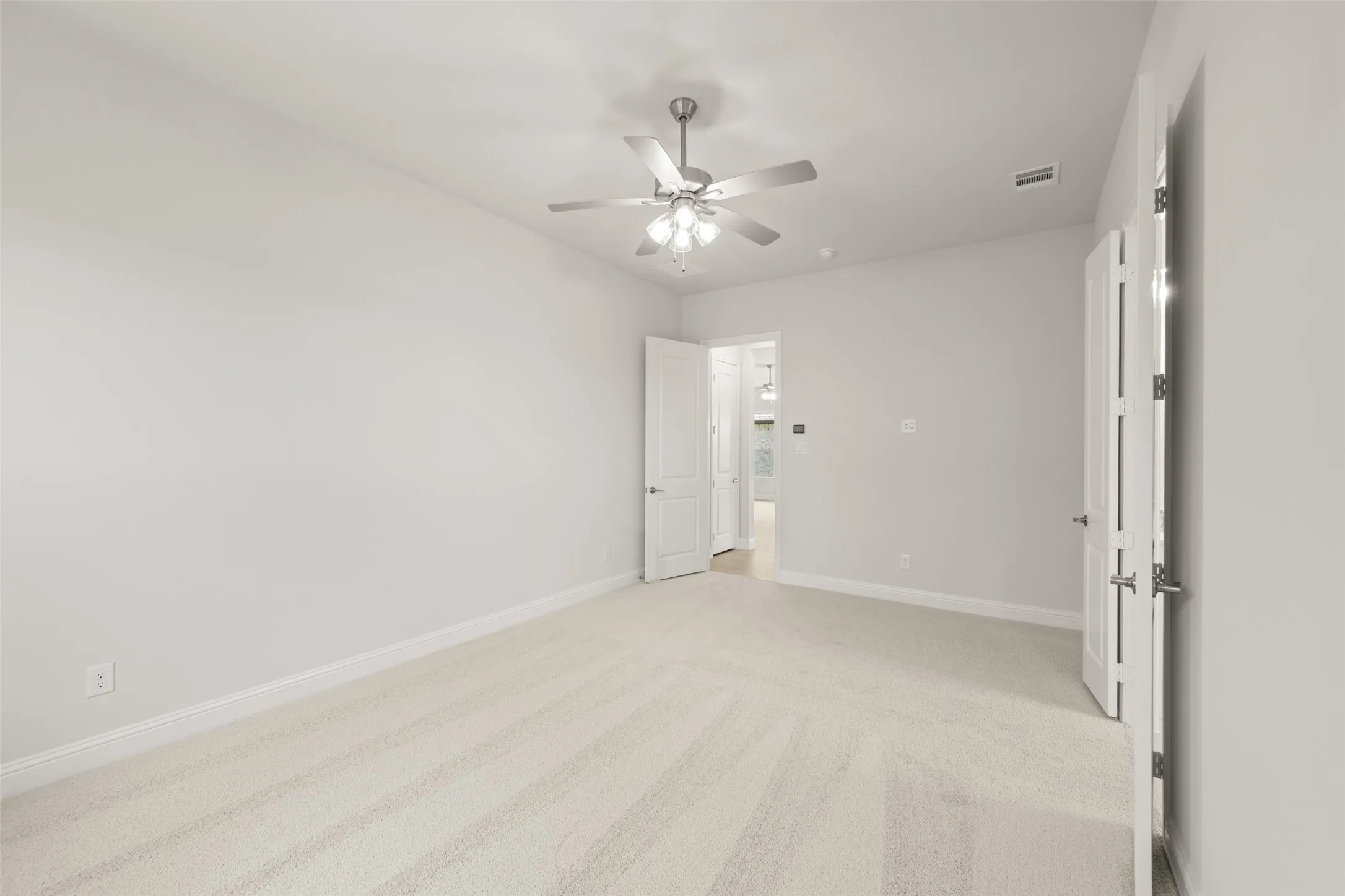 Unfurnished bedroom with light colored carpet and ceiling fan