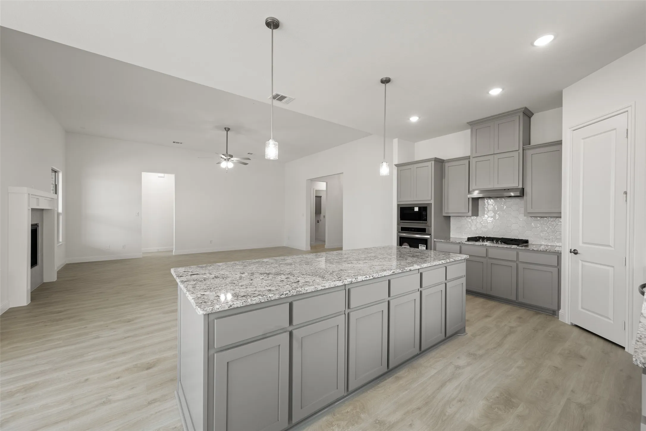Kitchen with gray cabinets, stainless steel appliances, decorative backsplash, a kitchen island, and recessed lighting