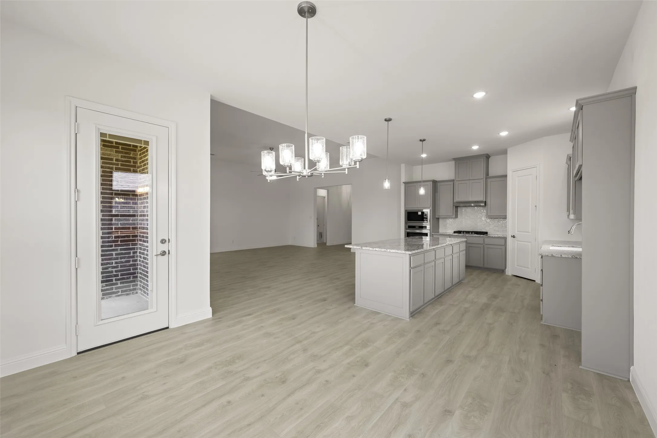 Kitchen with gray cabinets, a chandelier, a kitchen island, light wood-style flooring, and recessed lighting