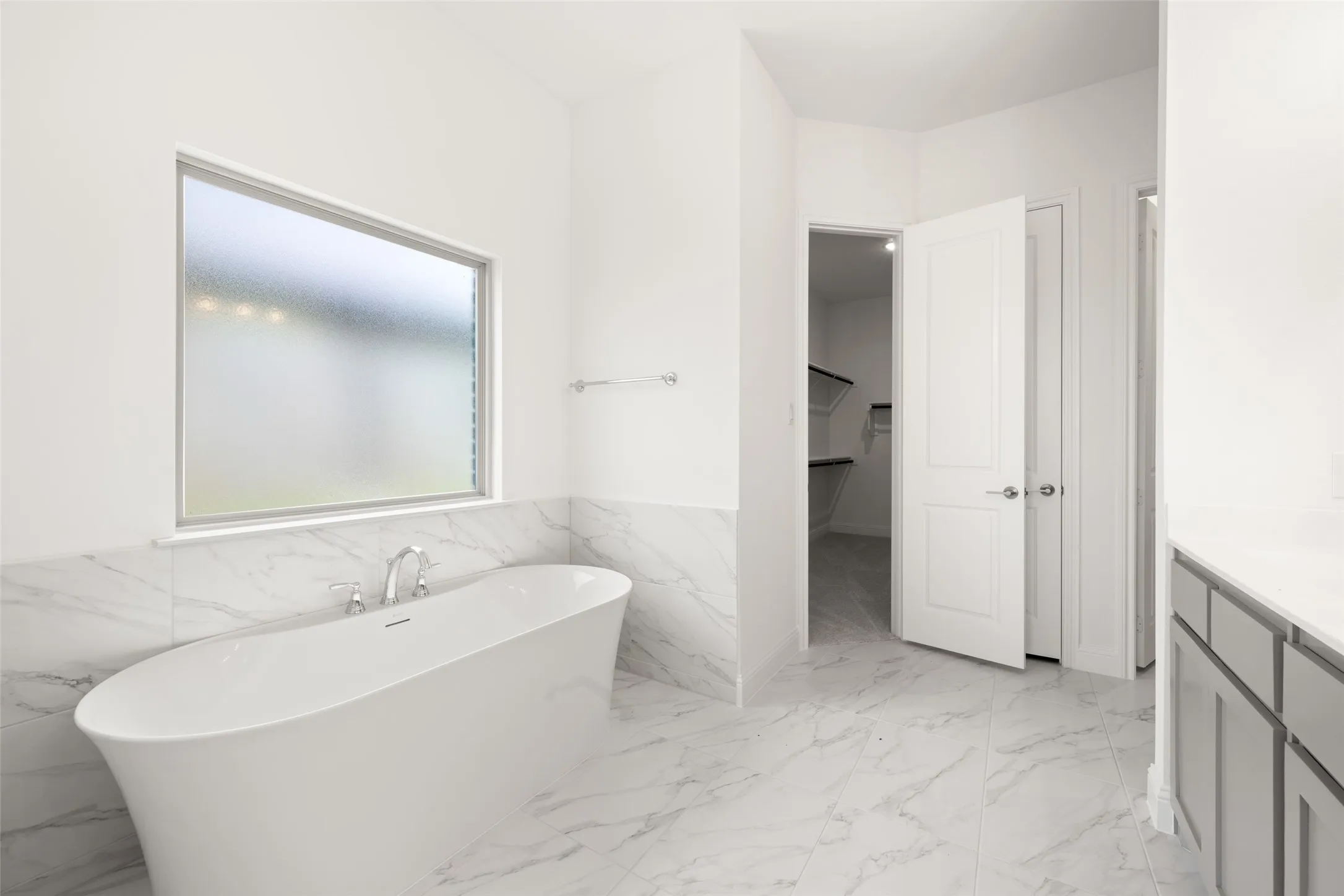 Full bathroom with a freestanding bath, vanity, marble finish floors, a closet, and a wainscoted wall