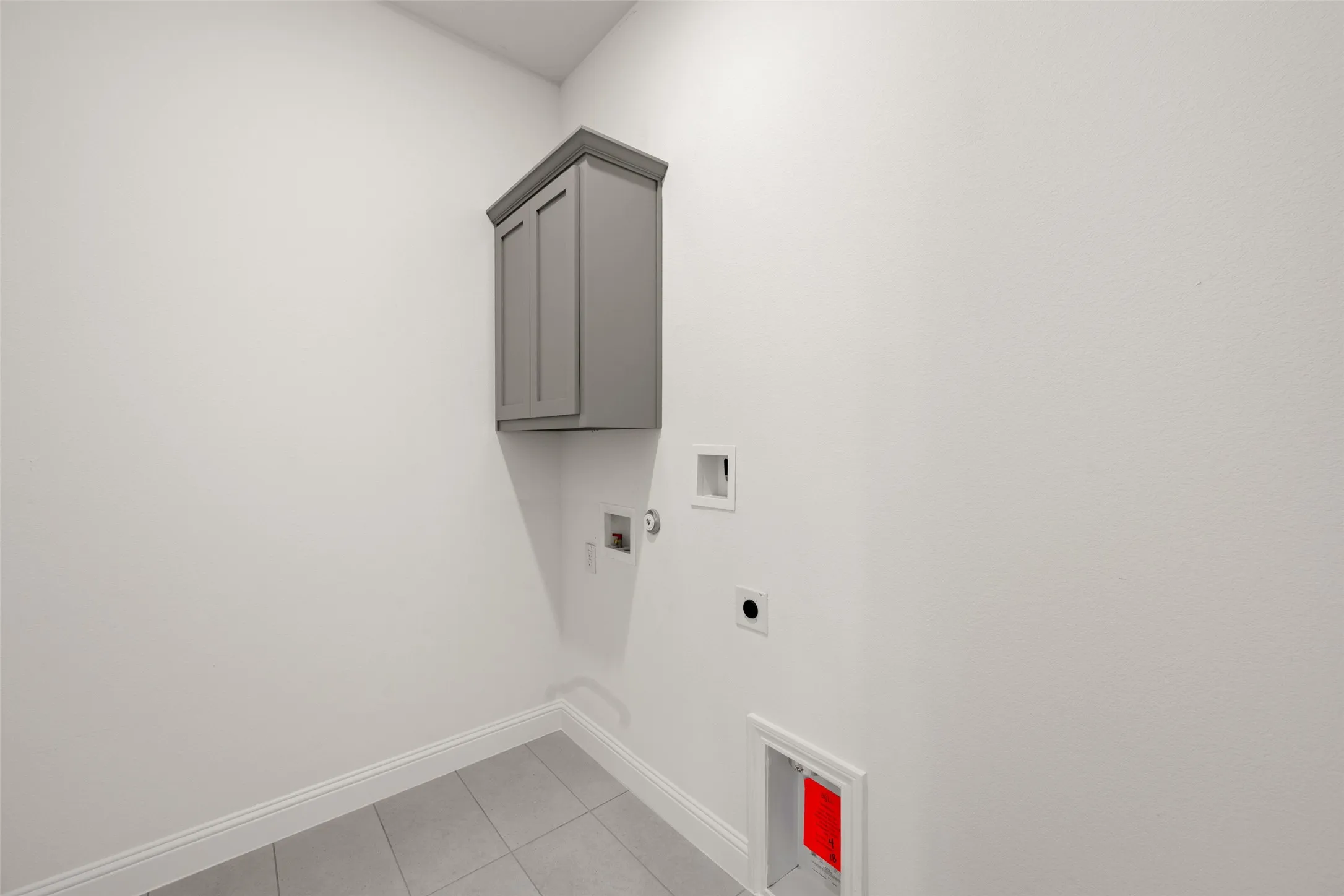 Laundry room featuring hookup for an electric dryer, cabinet space, washer hookup, and light tile patterned floors
