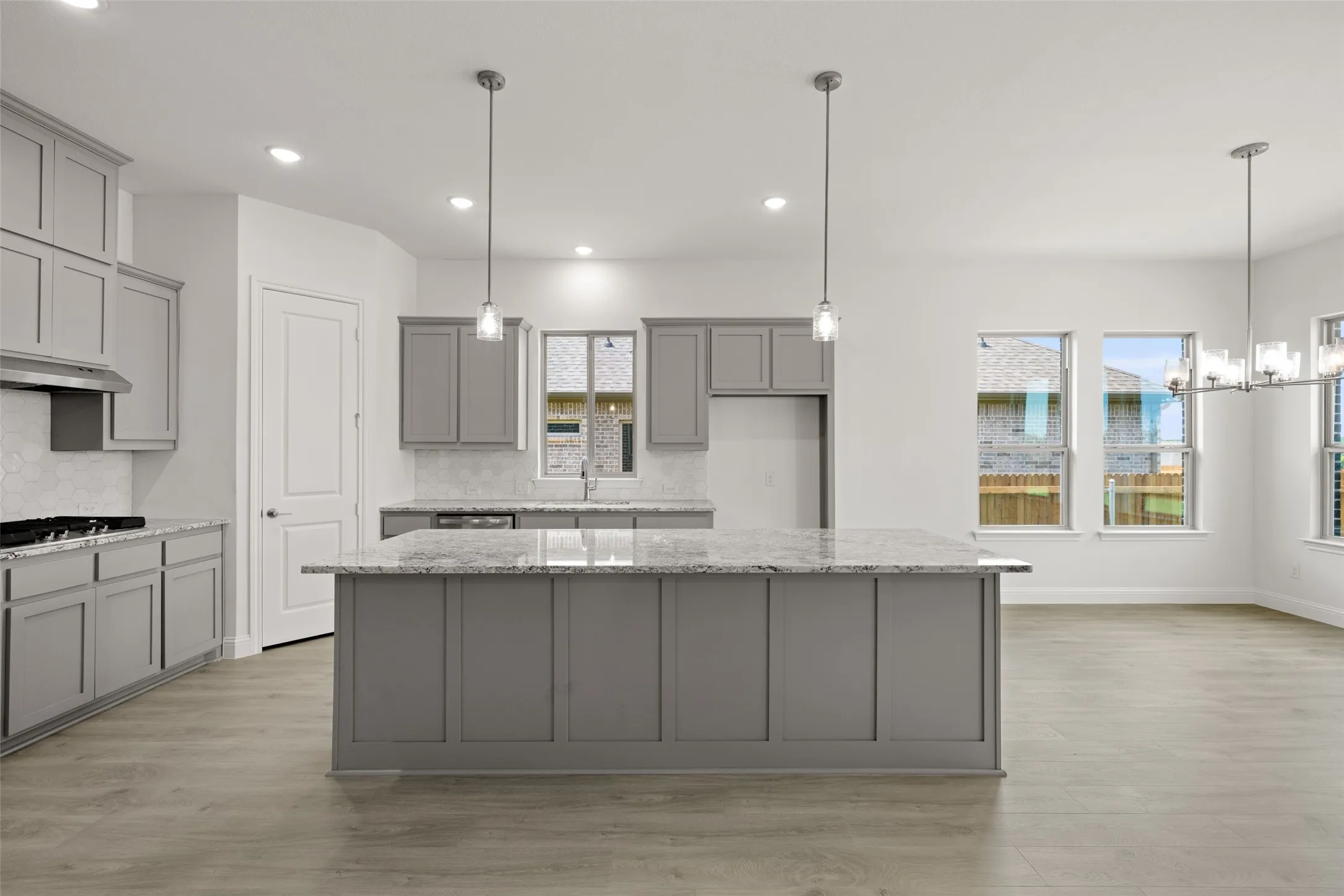 Kitchen with gray cabinets, tasteful backsplash, light wood-style flooring, a center island, and stainless steel gas cooktop