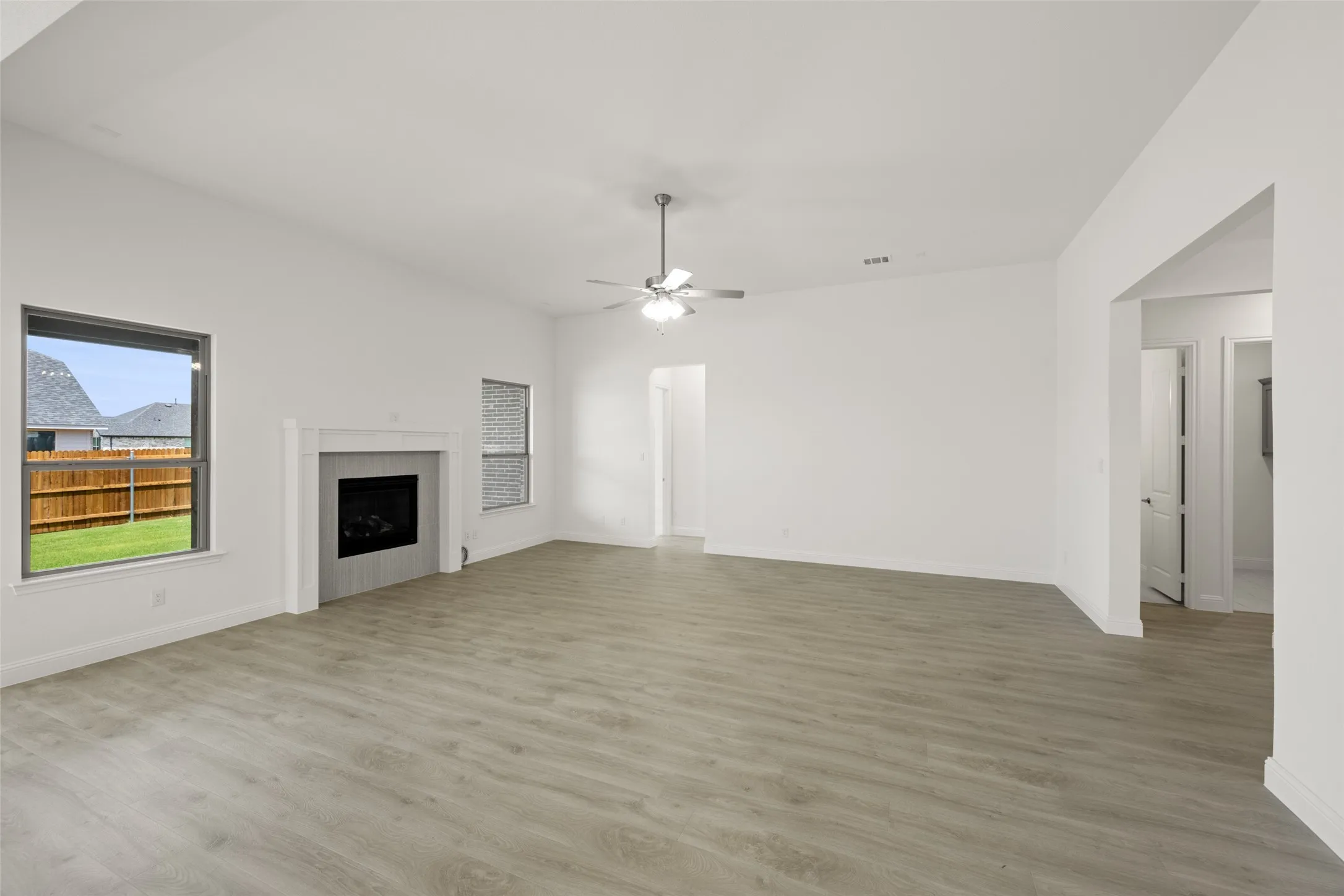 Unfurnished living room with light wood-style flooring, a ceiling fan, and a fireplace