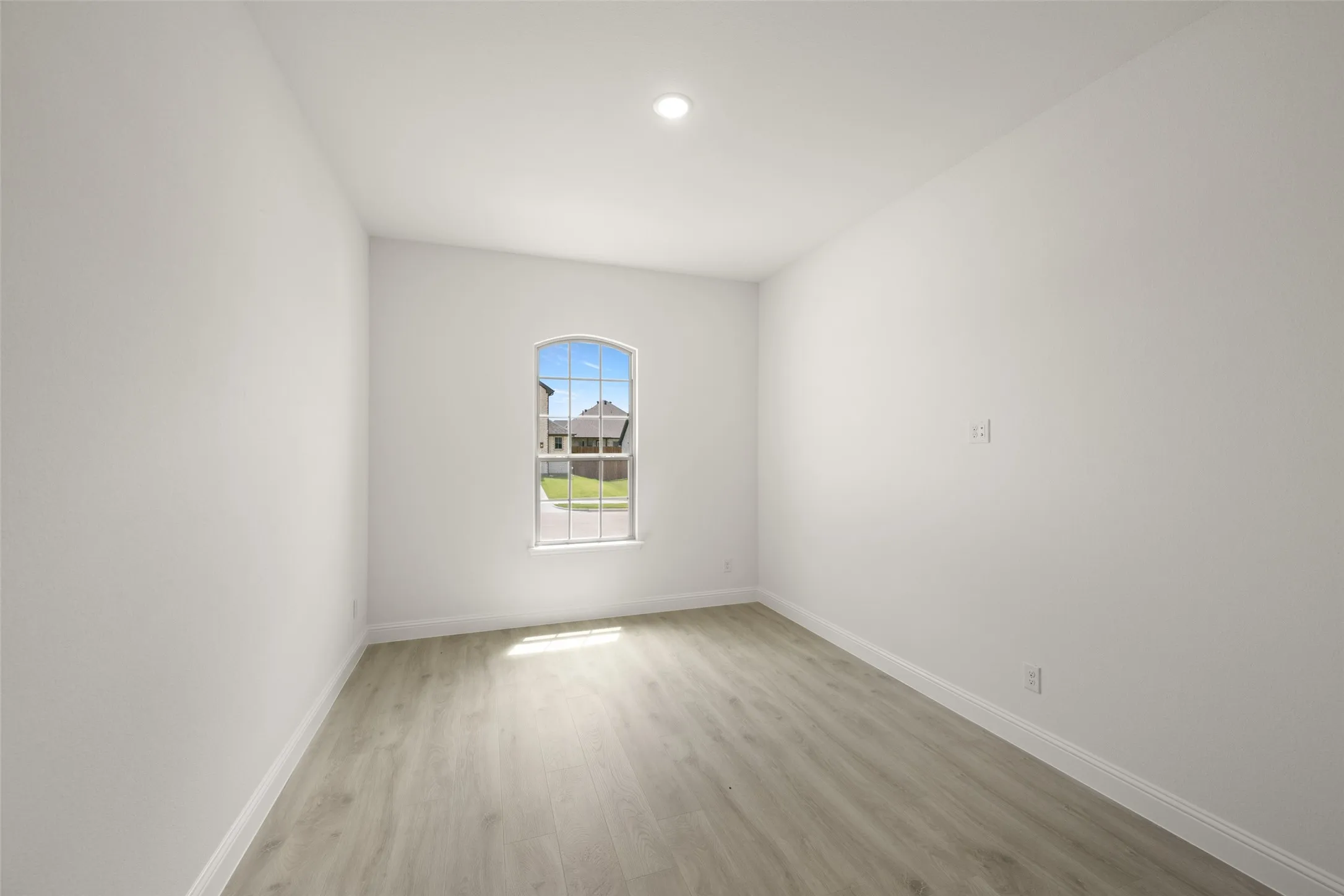 Empty room with light wood finished floors and recessed lighting