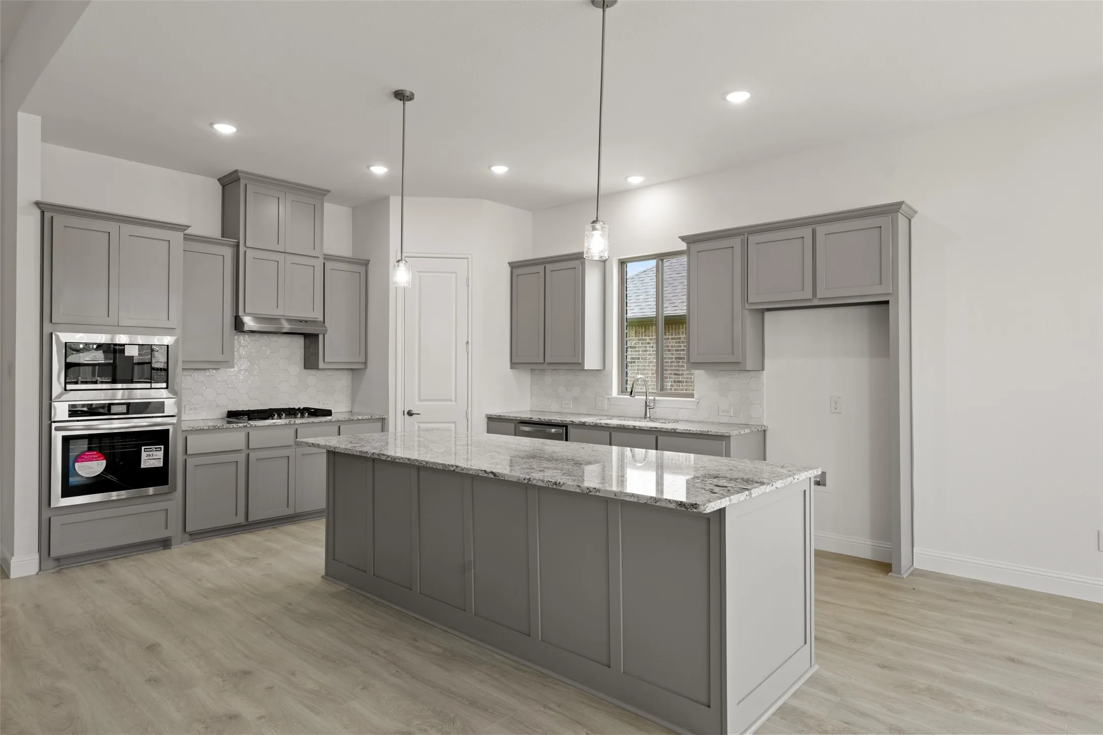 Kitchen featuring appliances with stainless steel finishes, gray cabinets, a center island, backsplash, and recessed lighting