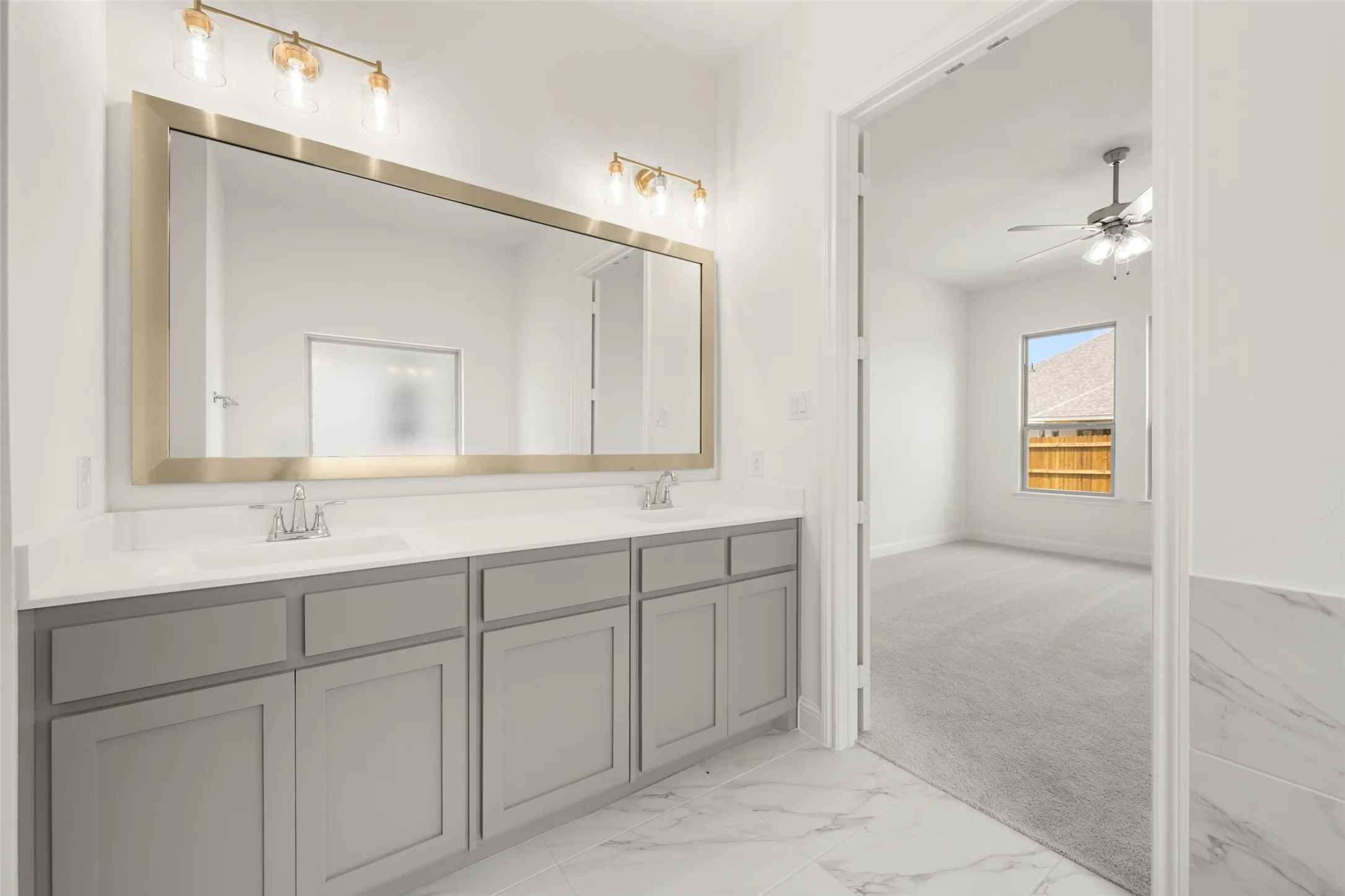 Bathroom with double vanity, marble finish floors, and ceiling fan
