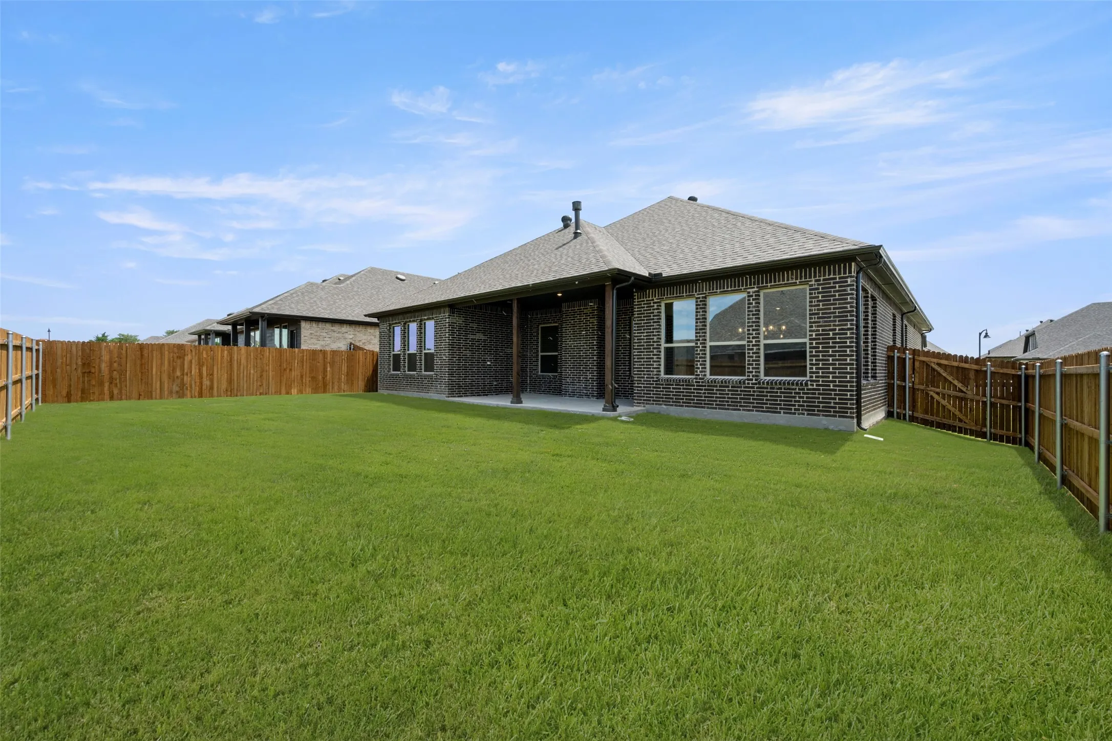 Back of house with a fenced backyard, brick siding, and a shingled roof