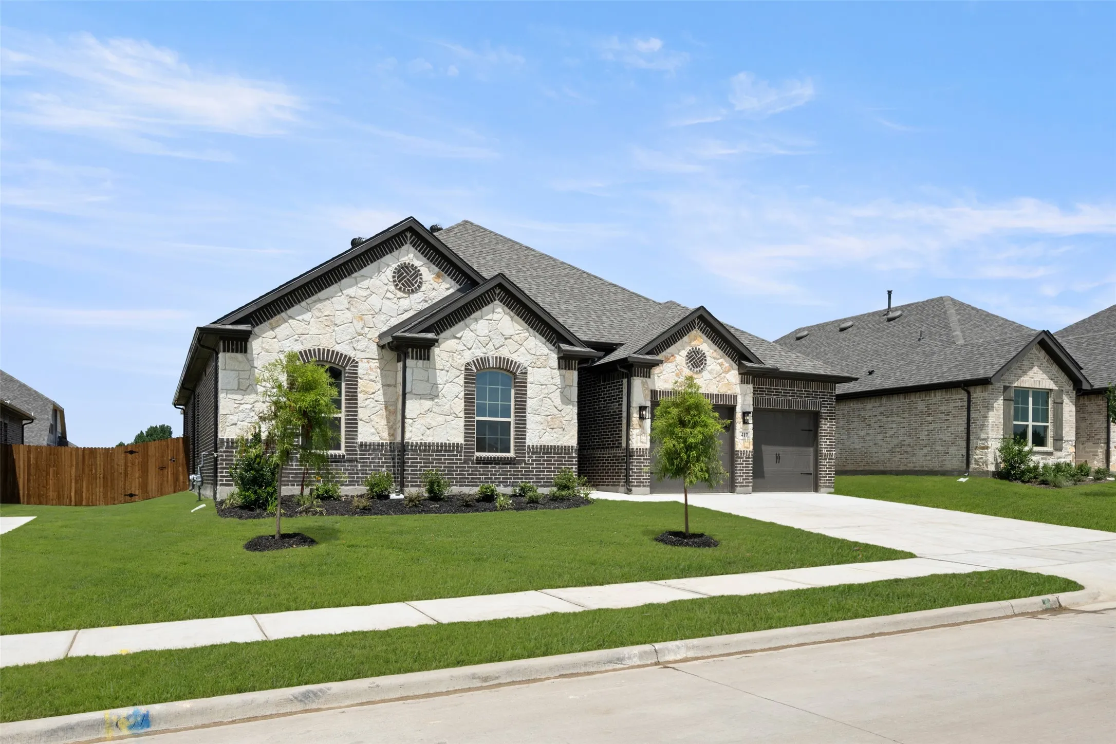 French country style house with stone siding, driveway, a garage, and roof with shingles
