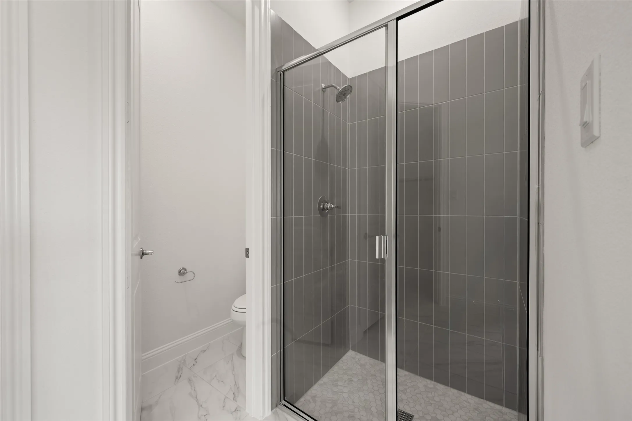 Bathroom featuring marble look tiles and a shower stall