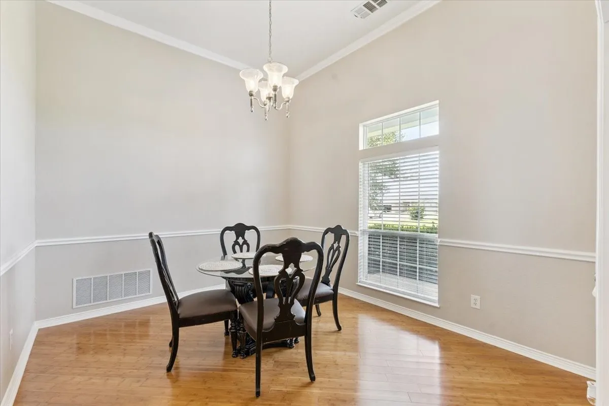 Dining room featuring ornamental molding, wood finished floors, and a chandelier