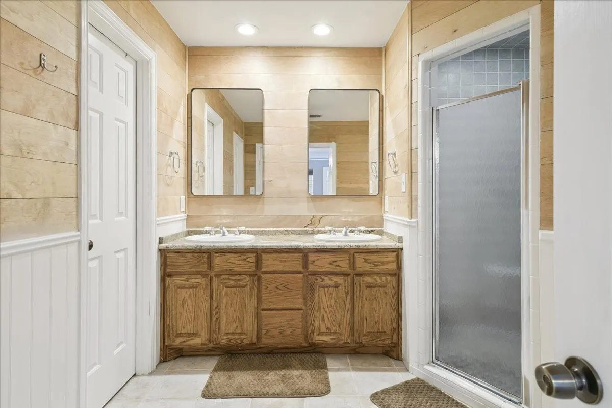 Full bath with a stall shower, double vanity, and tile patterned floors