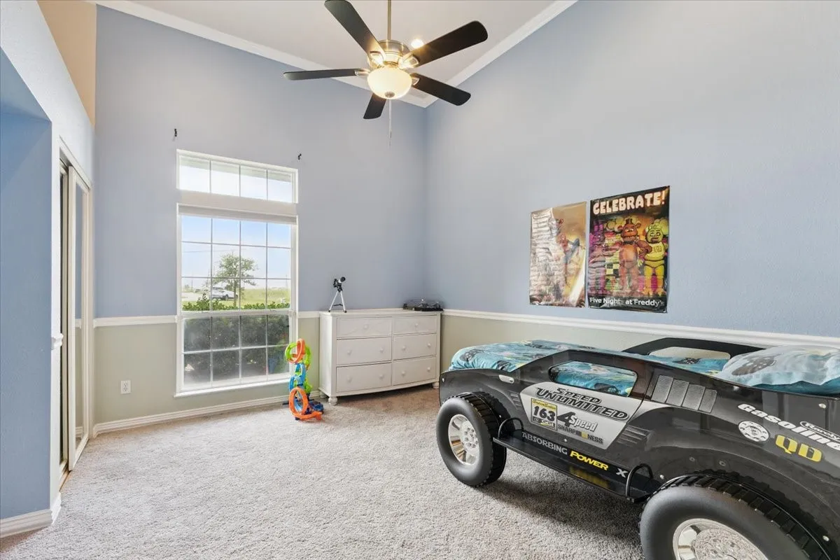 Carpeted bedroom featuring a towering ceiling, ornamental molding, and ceiling fan