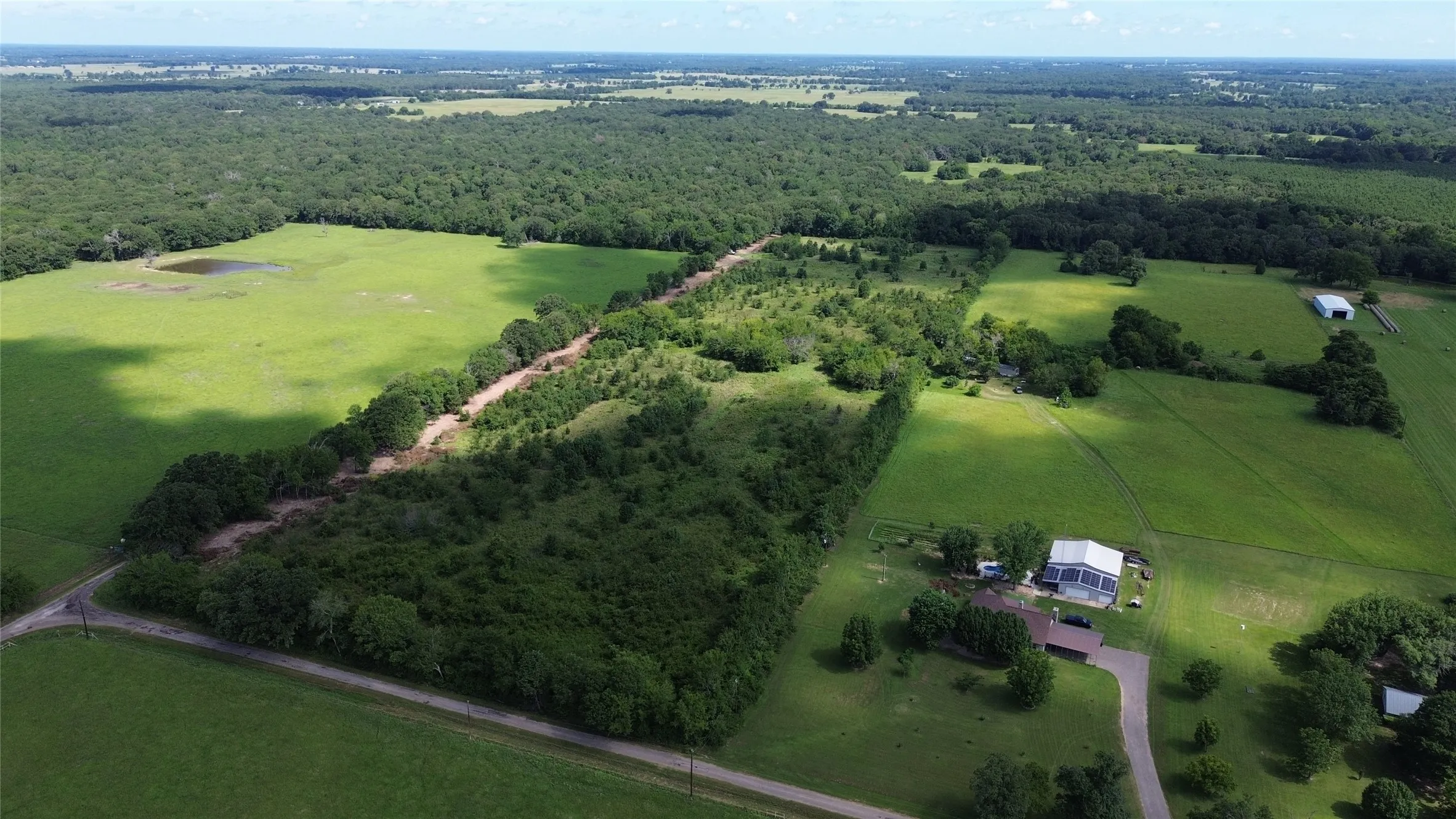 Aerial view of property's location featuring rural landscape and a forest