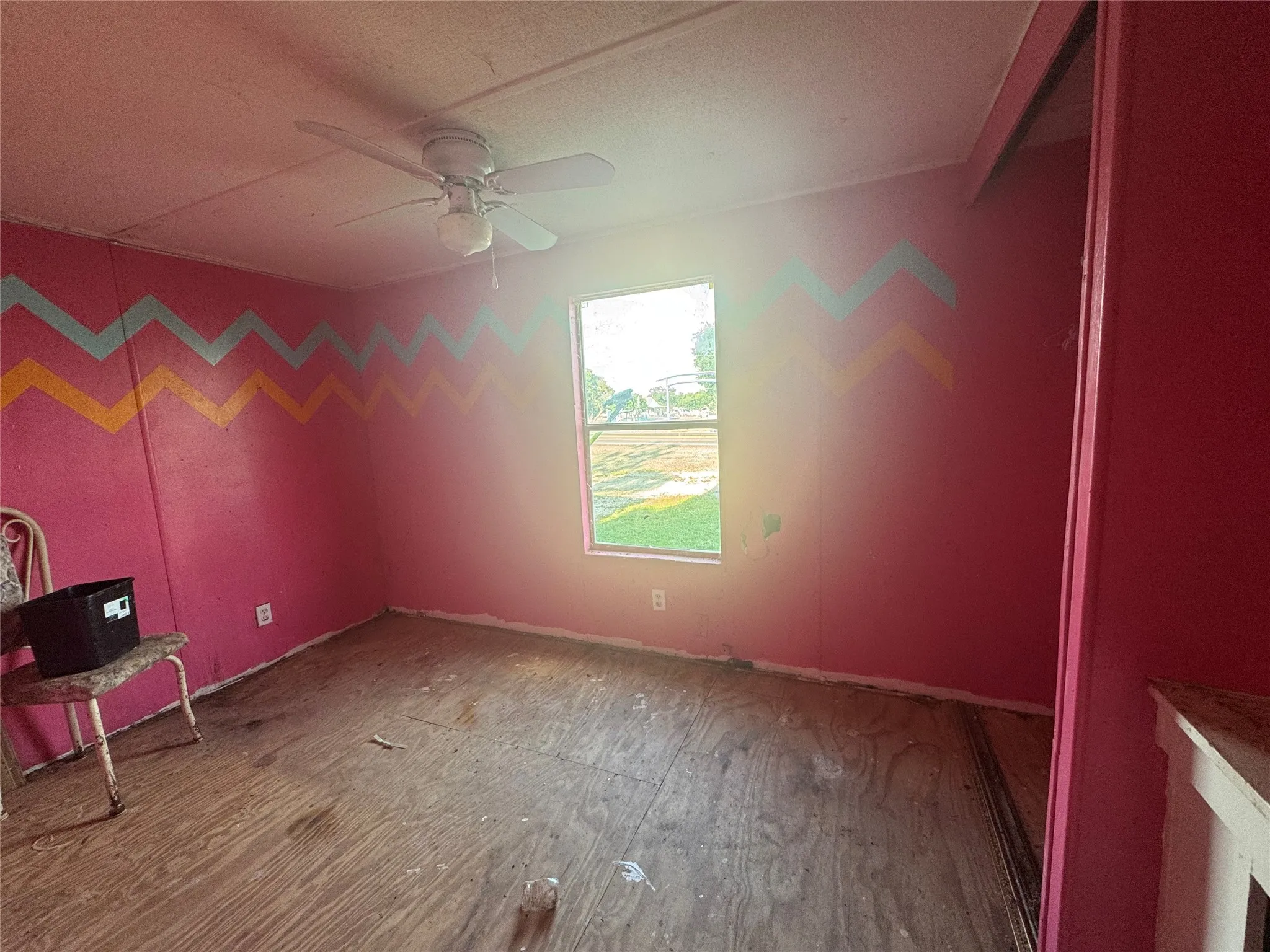Unfurnished room with a ceiling fan, wood finished floors, and a textured ceiling