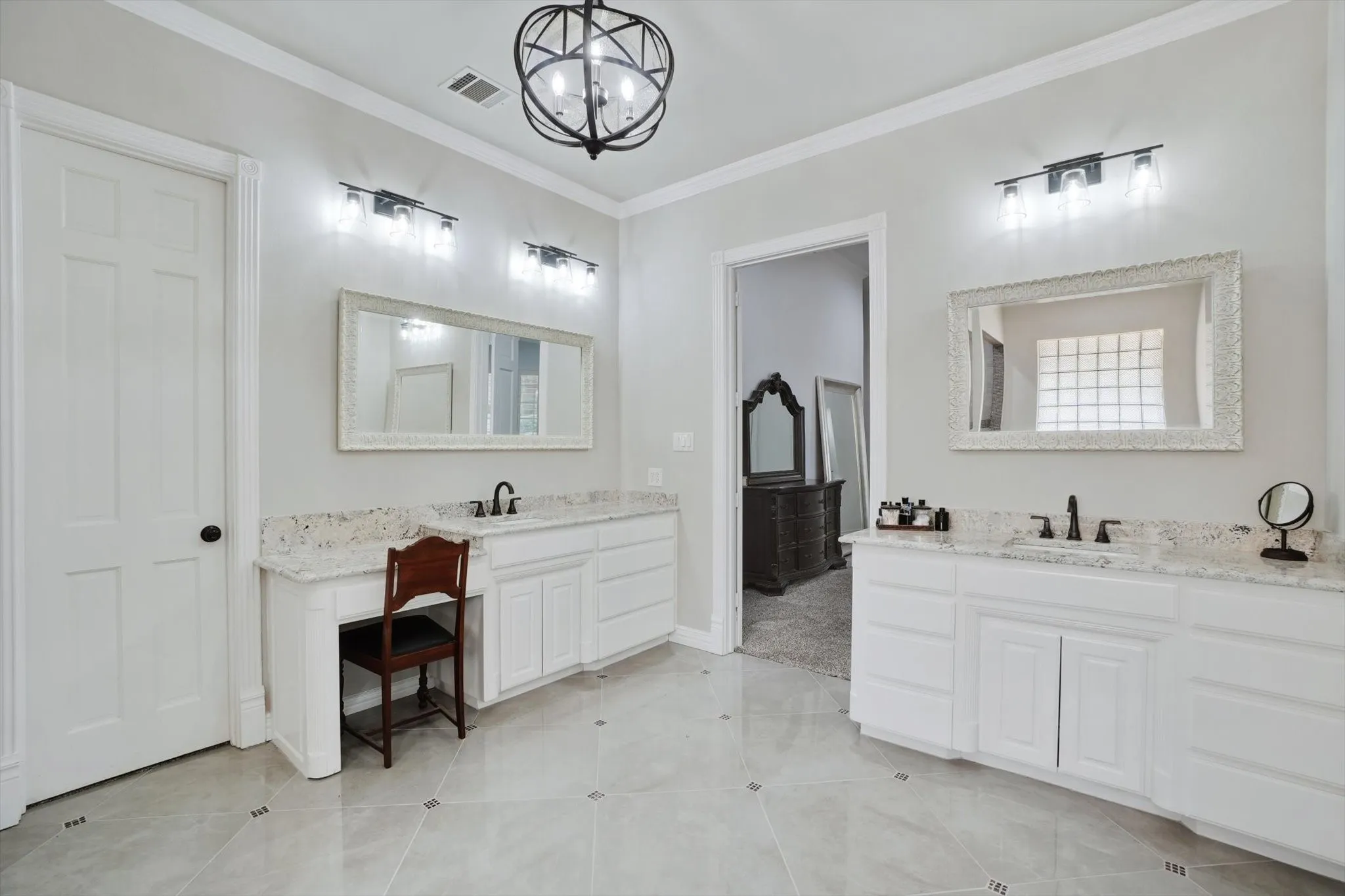 Full bath with ornamental molding, a chandelier, two vanities, and tile patterned floors