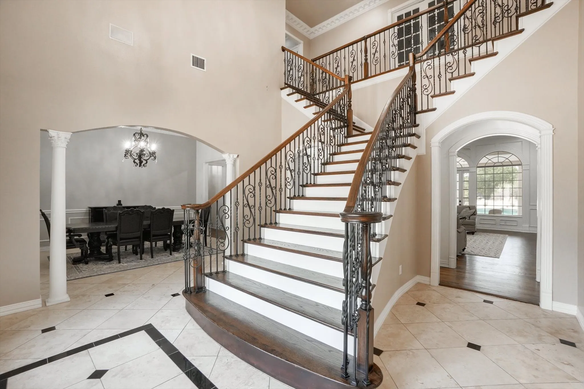Stairway featuring arched walkways, a high ceiling, tile patterned floors, a chandelier, and decorative columns