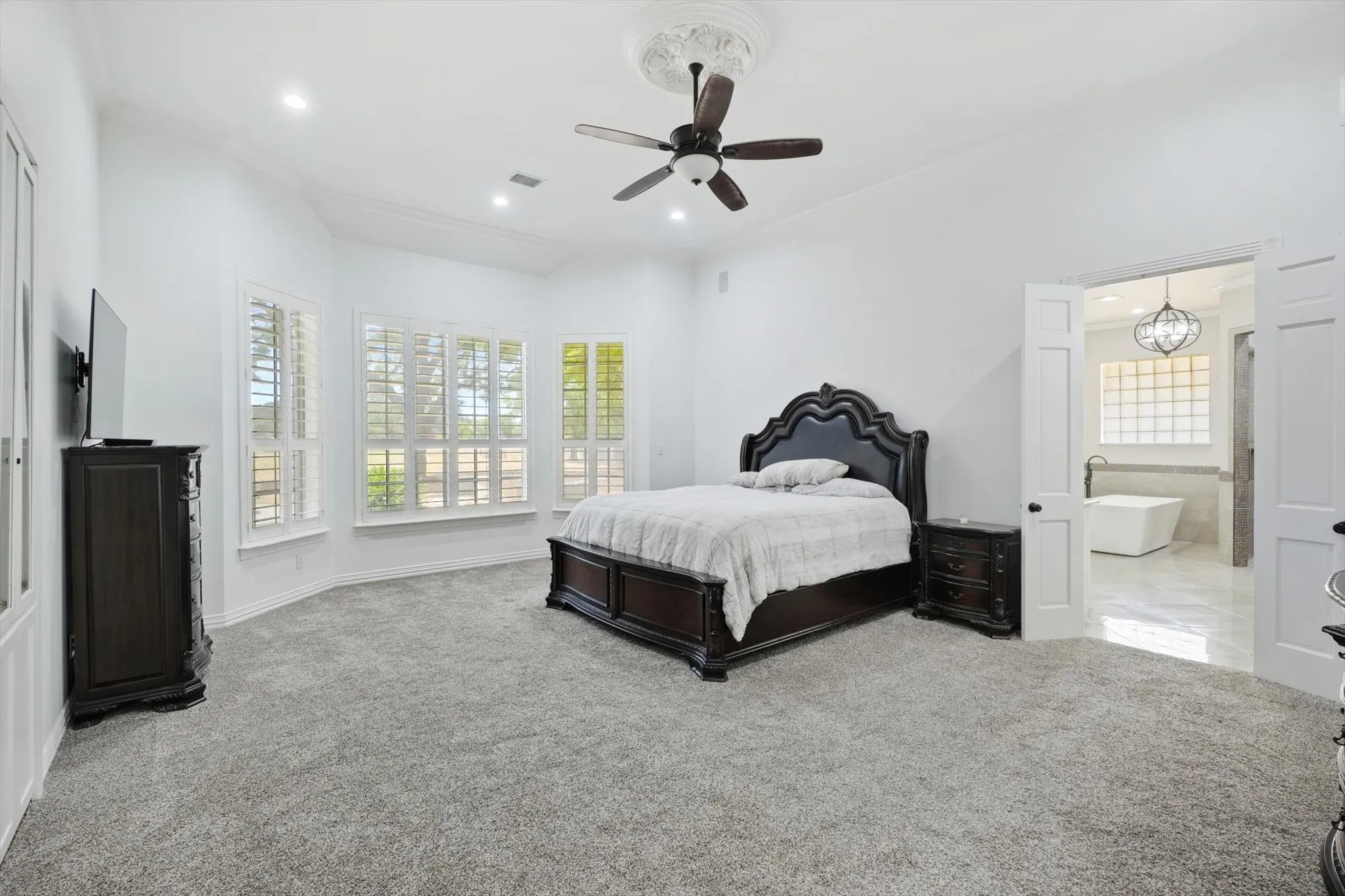 Bedroom with carpet floors, recessed lighting, ornamental molding, a ceiling fan, and ensuite bath