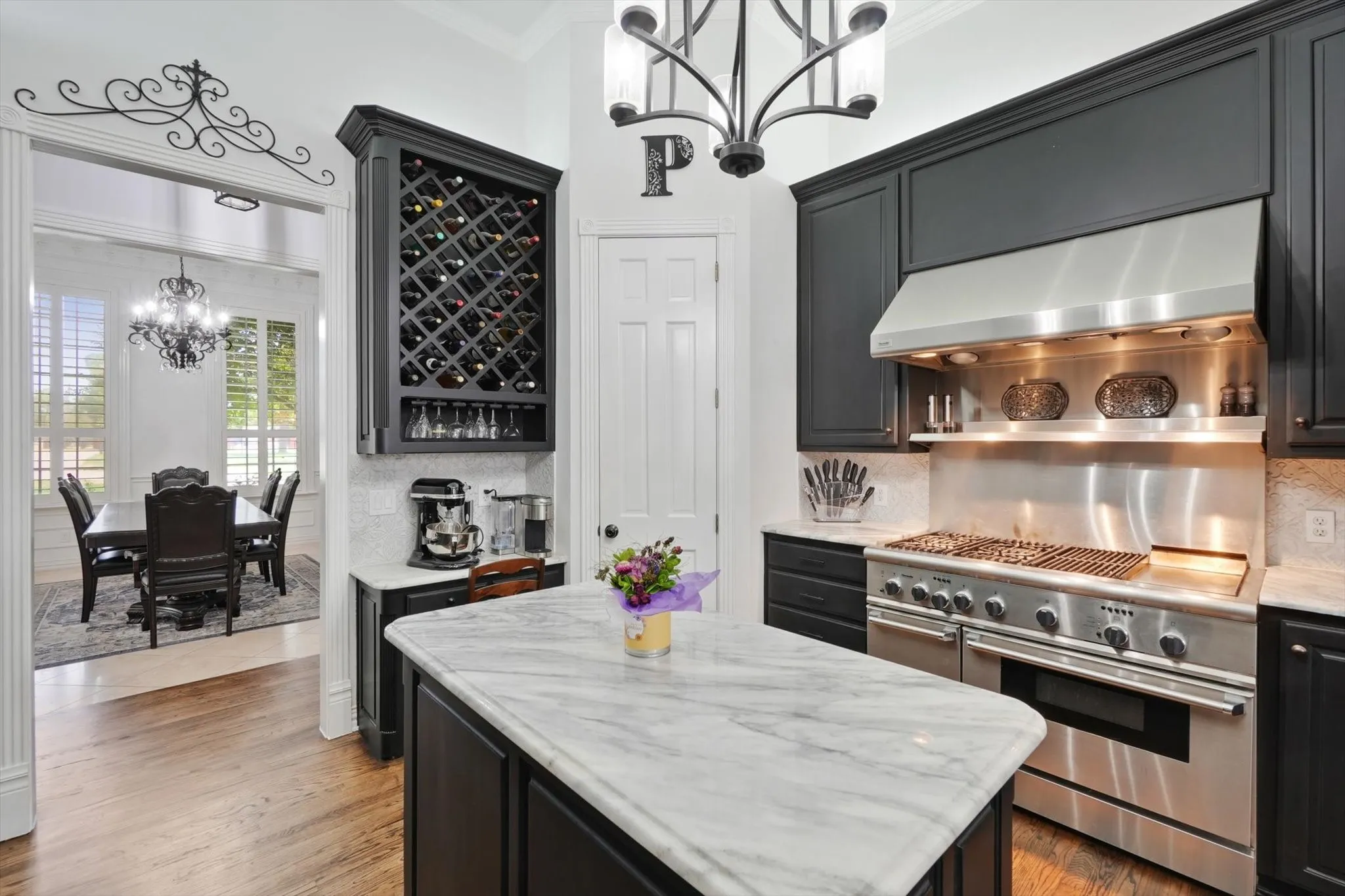 Kitchen with a chandelier, ventilation hood, double oven range, tasteful backsplash, and crown molding