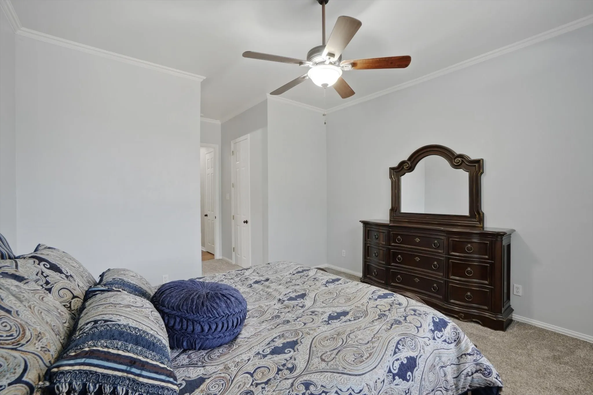 Carpeted bedroom featuring ornamental molding and a ceiling fan