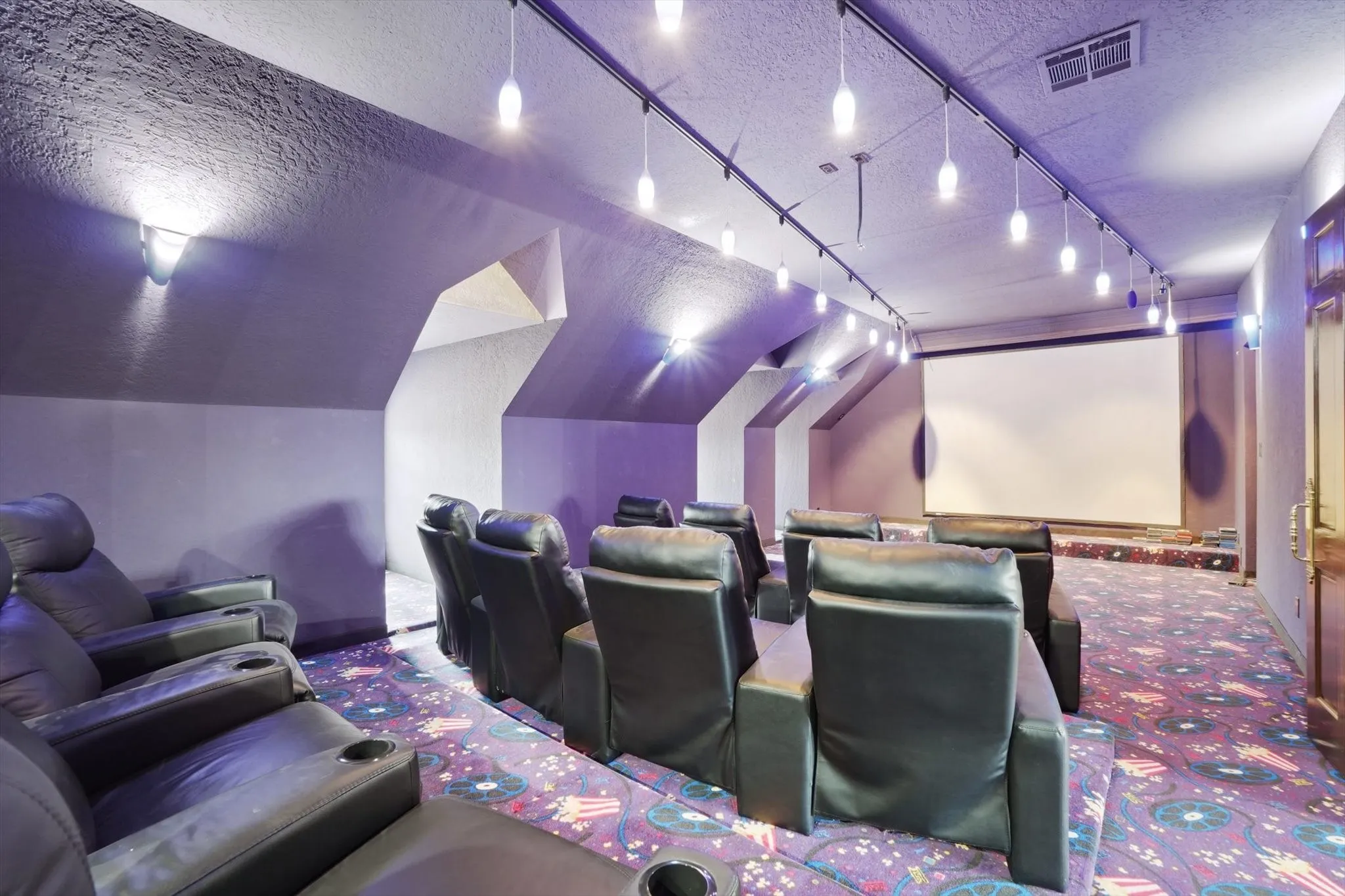 Carpeted cinema featuring a textured ceiling and track lighting