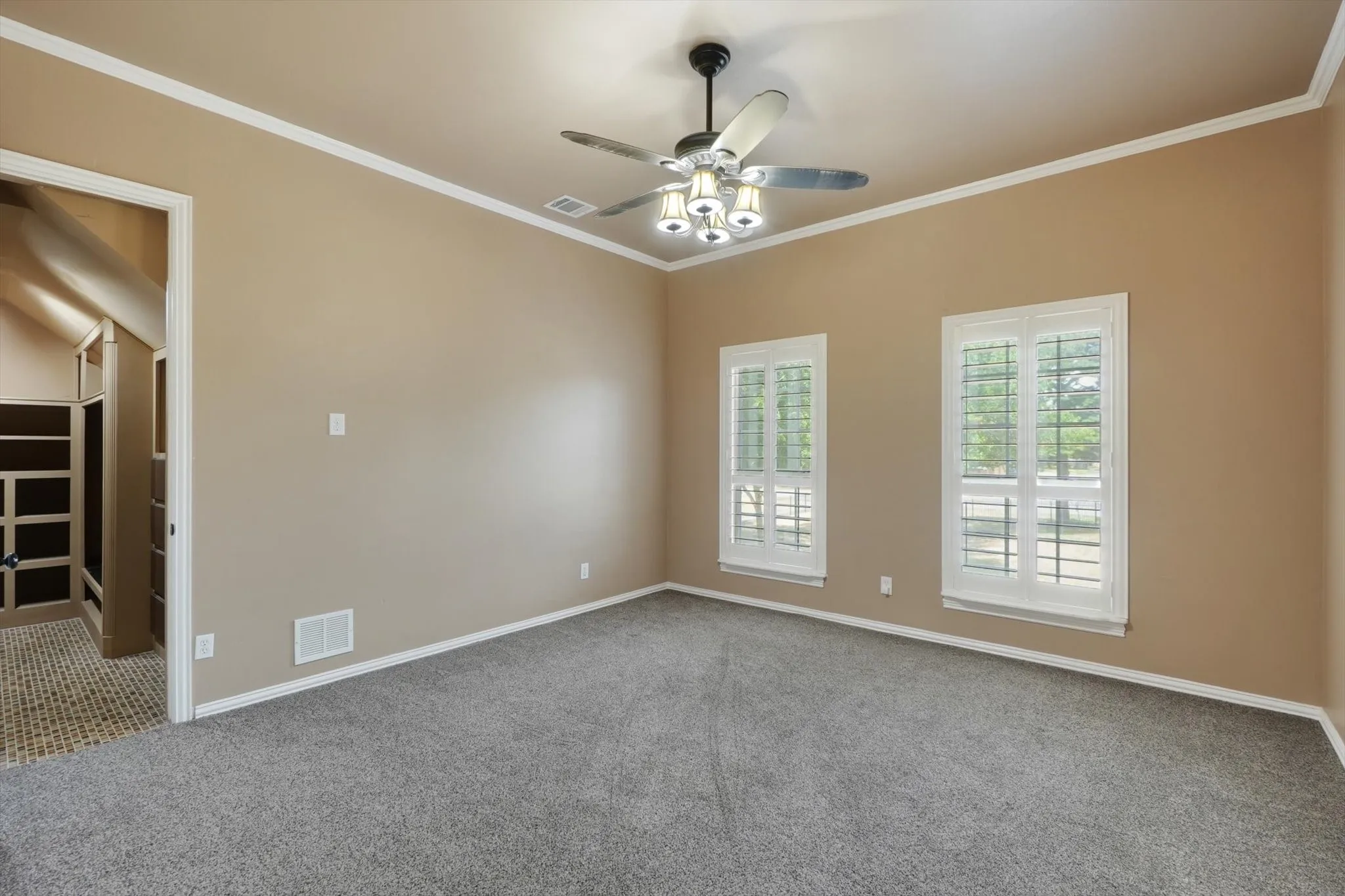 Empty room featuring carpet floors, ceiling fan, and crown molding