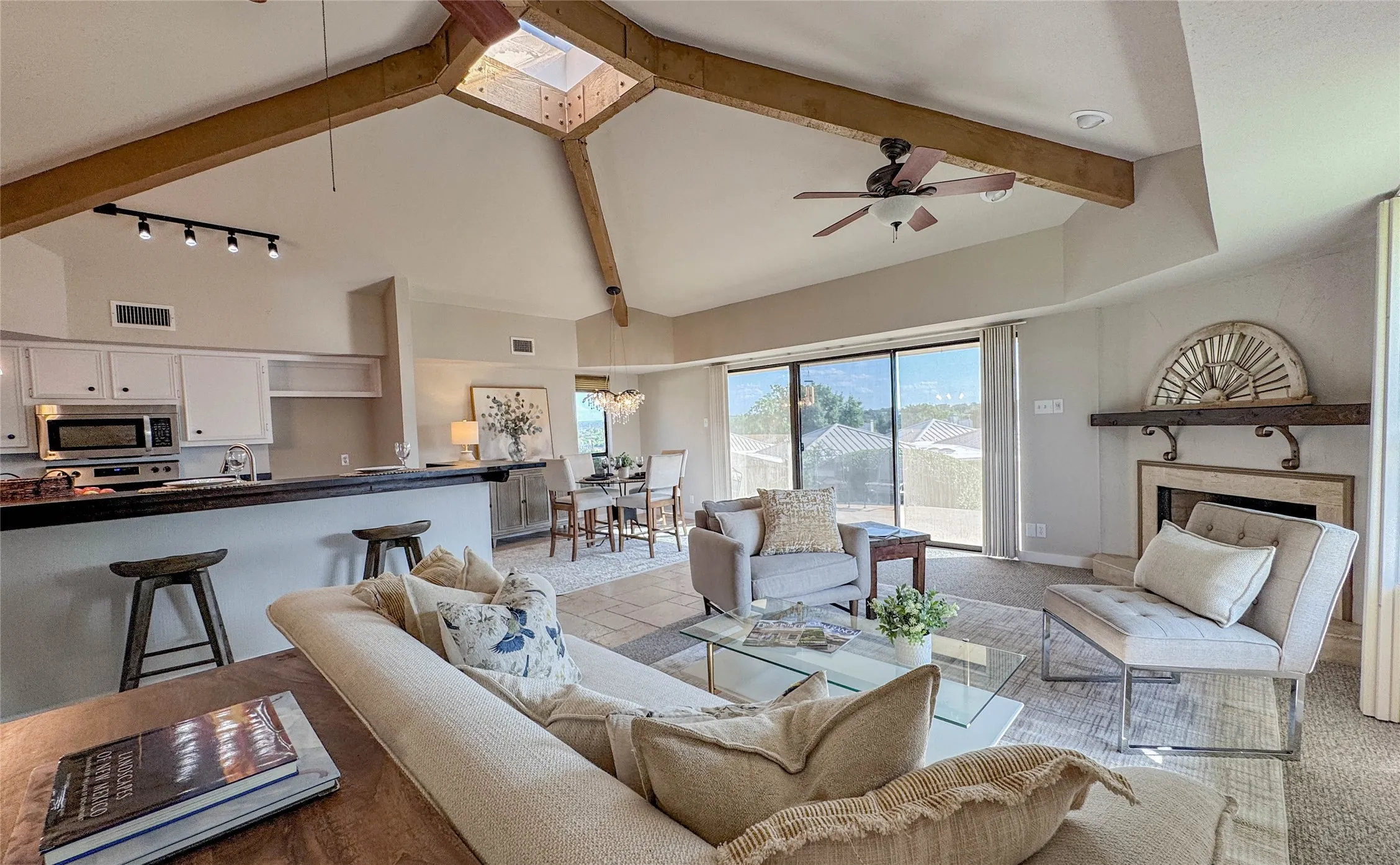 Living room with high vaulted ceiling, beamed ceiling, a ceiling fan, rail lighting, and a fireplace