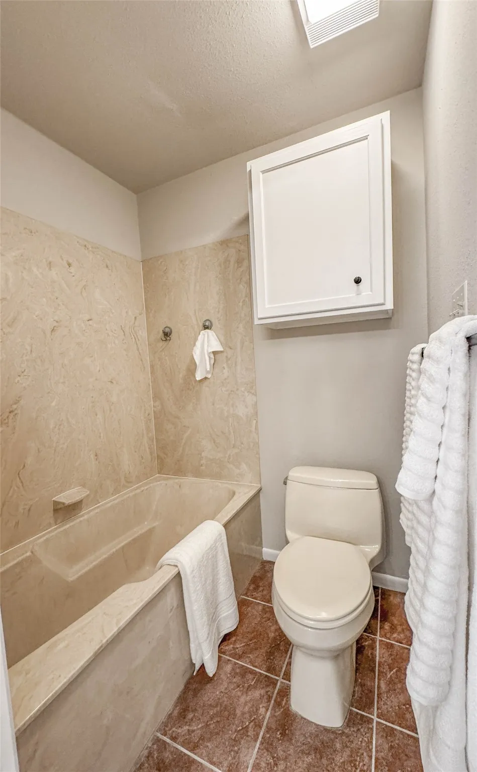 Bathroom with a tub with marble appearance and tile patterned floors