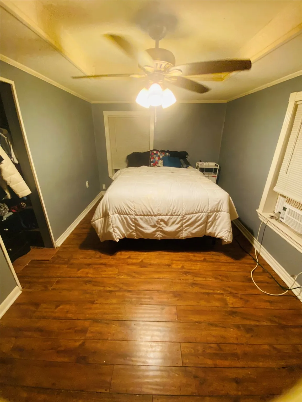 Bedroom featuring hardwood / wood-style flooring, ornamental molding, and ceiling fan