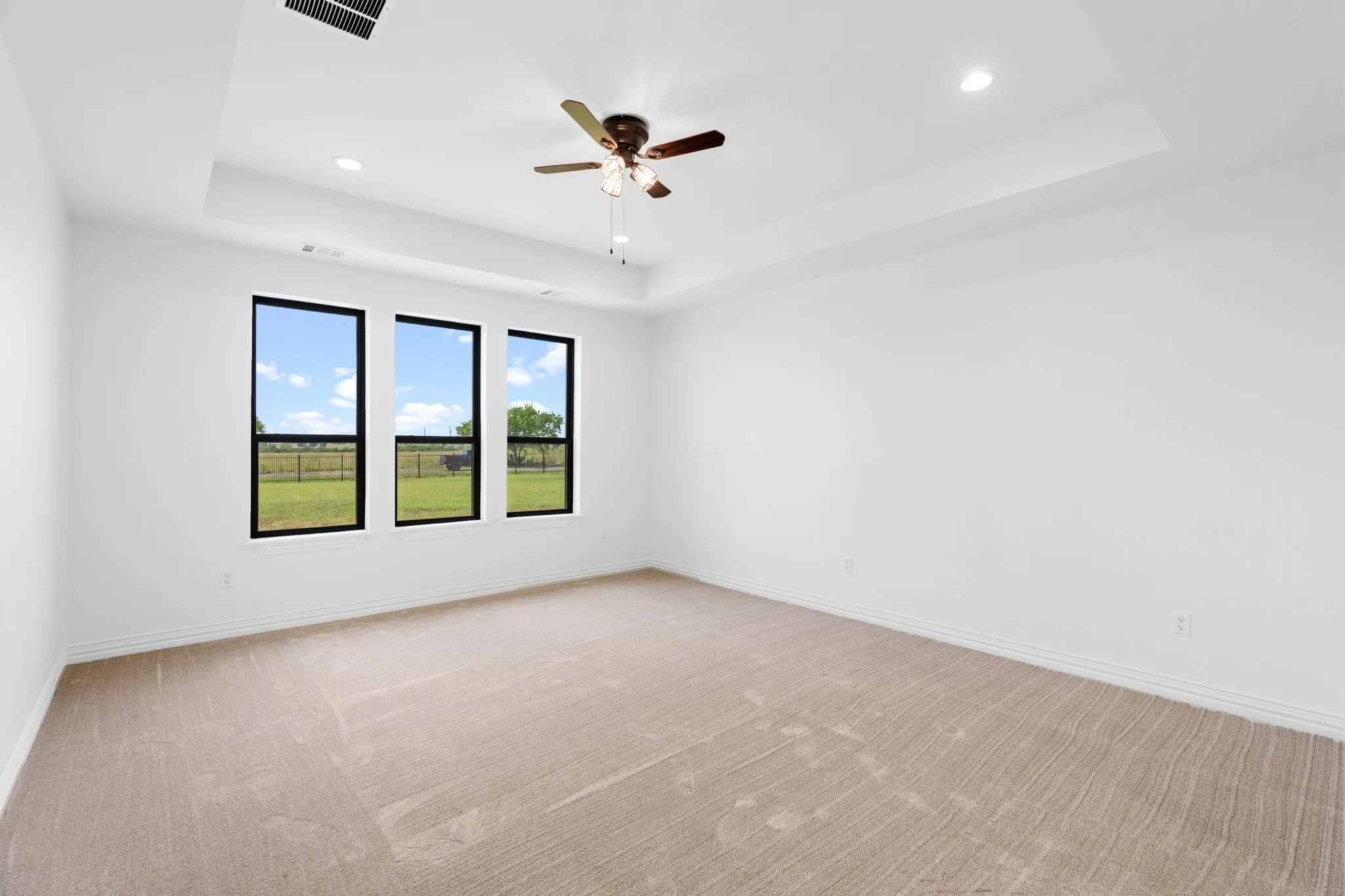 Unfurnished room featuring a tray ceiling, recessed lighting, light carpet, and a ceiling fan