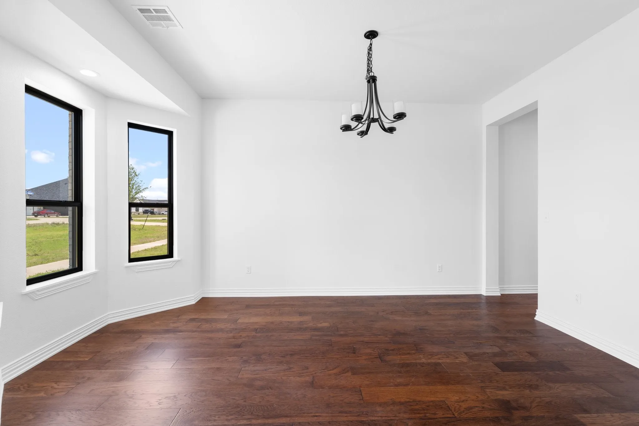 Unfurnished dining area featuring a chandelier and dark wood-type flooring