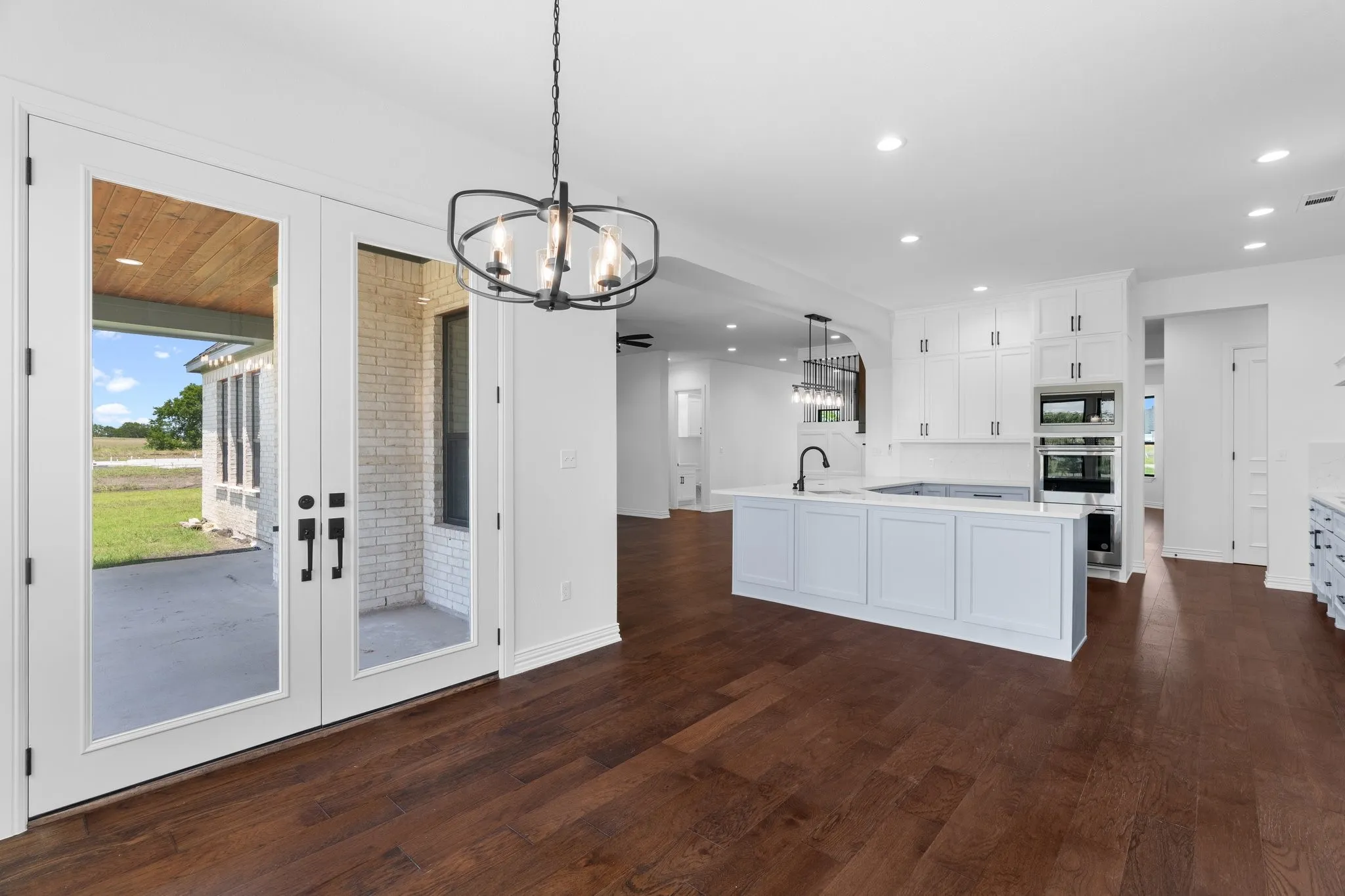 Kitchen featuring oven, a chandelier, black microwave, light countertops, and dark wood-style floors