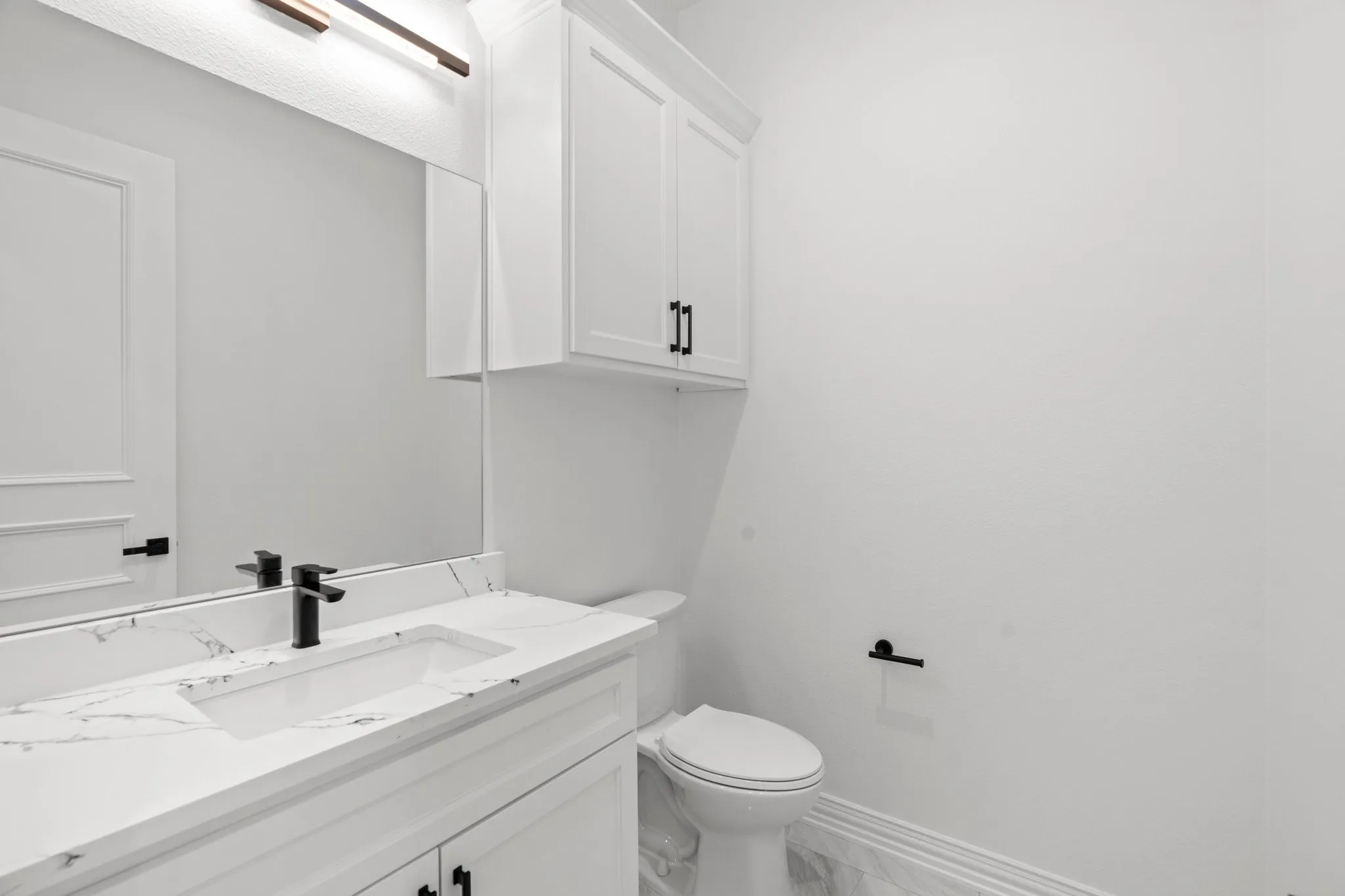 Half bath featuring vanity and marble finish flooring