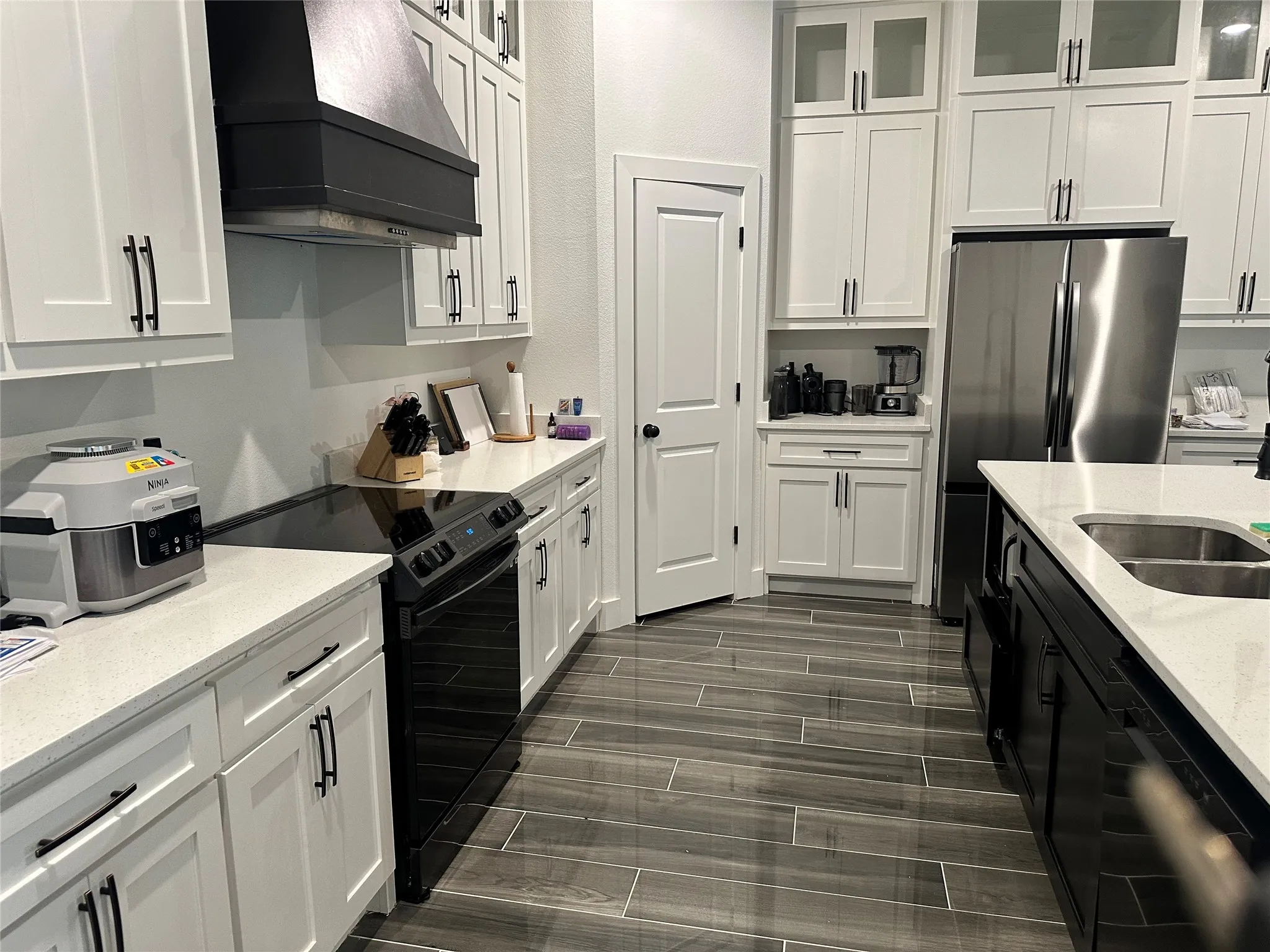 Kitchen with wall chimney exhaust hood, electric range, dishwasher, and white cabinets