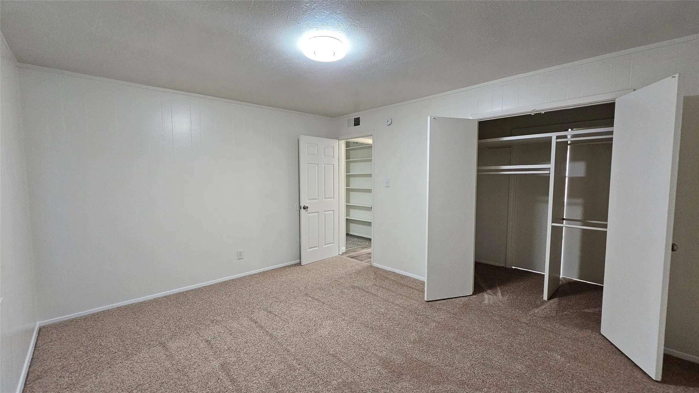 Unfurnished bedroom featuring carpet flooring, a closet, a textured ceiling, and ornamental molding