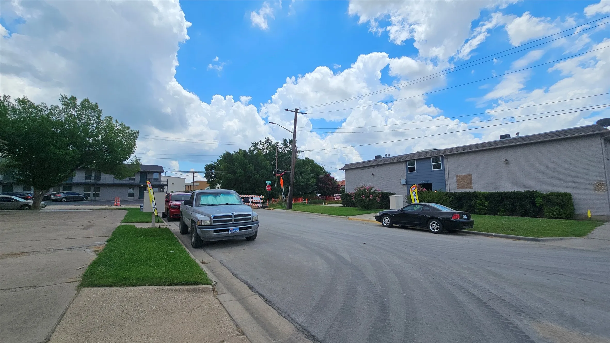 View of asphalt road with curbs, street lighting, sidewalks, and traffic signs