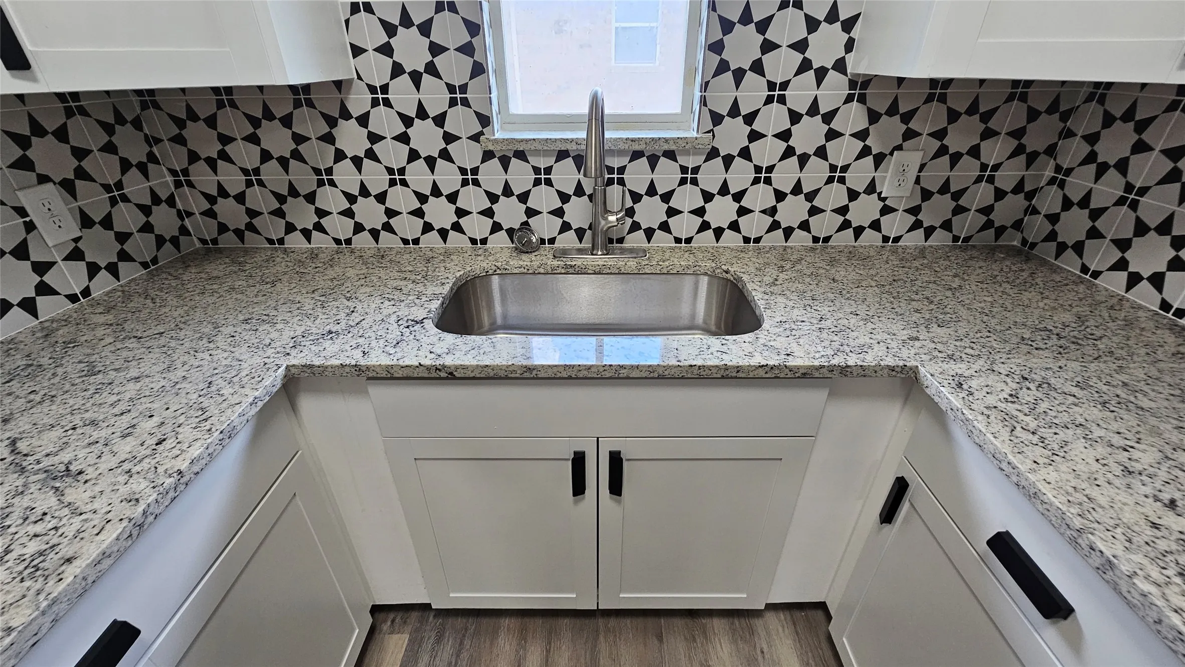 Kitchen featuring white cabinetry, decorative backsplash, wood finished floors, and light stone counters
