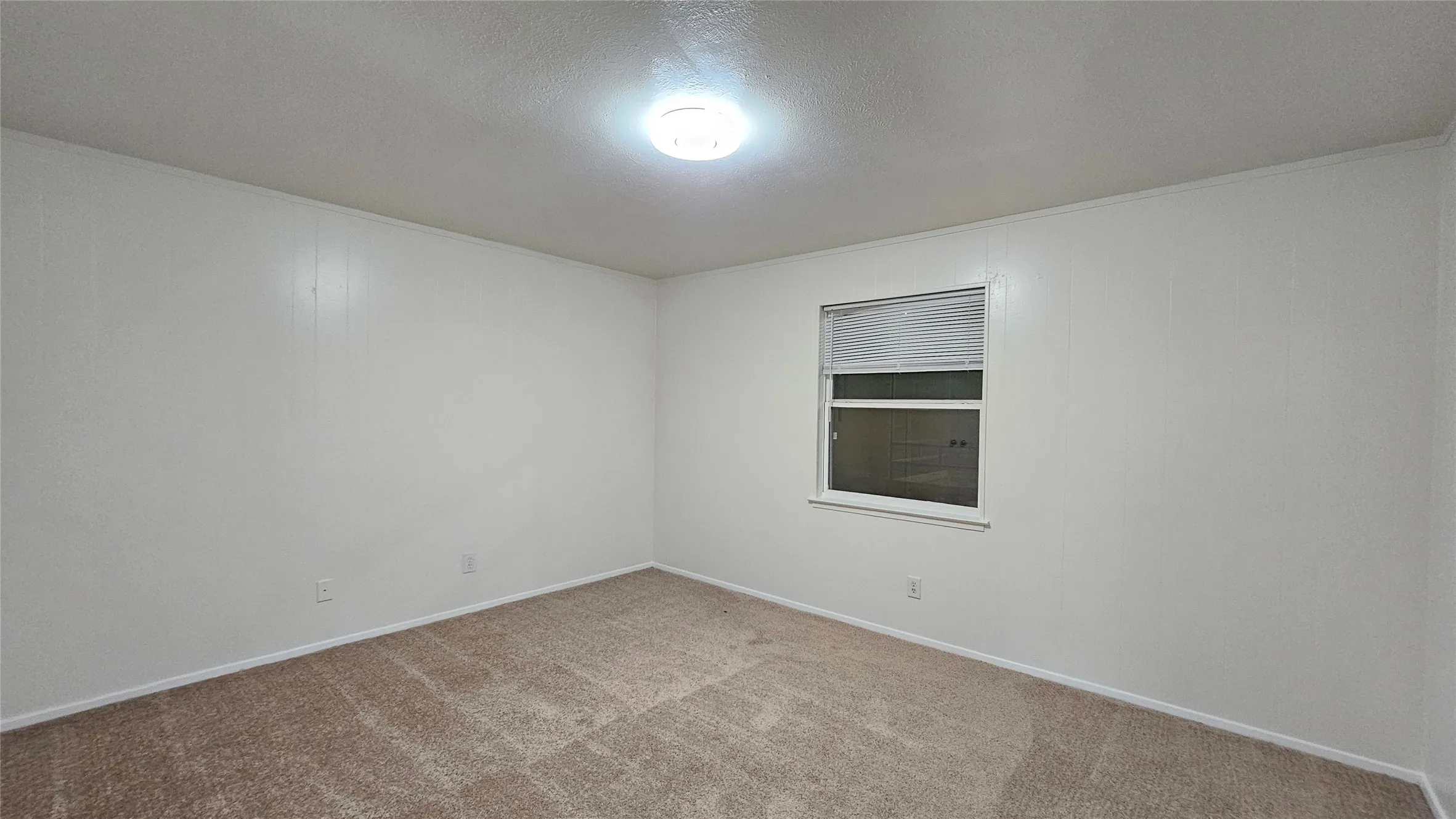 Carpeted empty room featuring baseboards and a textured ceiling