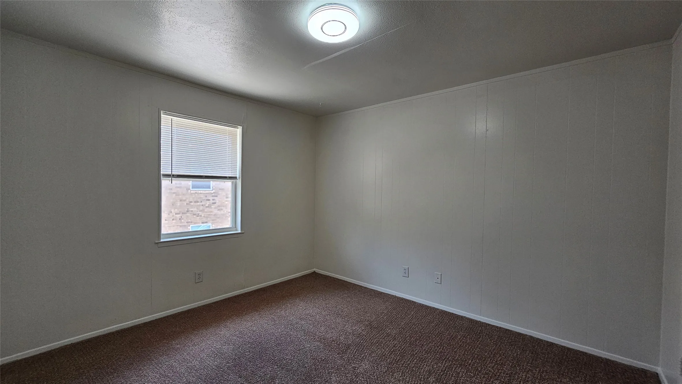 Unfurnished room featuring dark carpet and baseboards