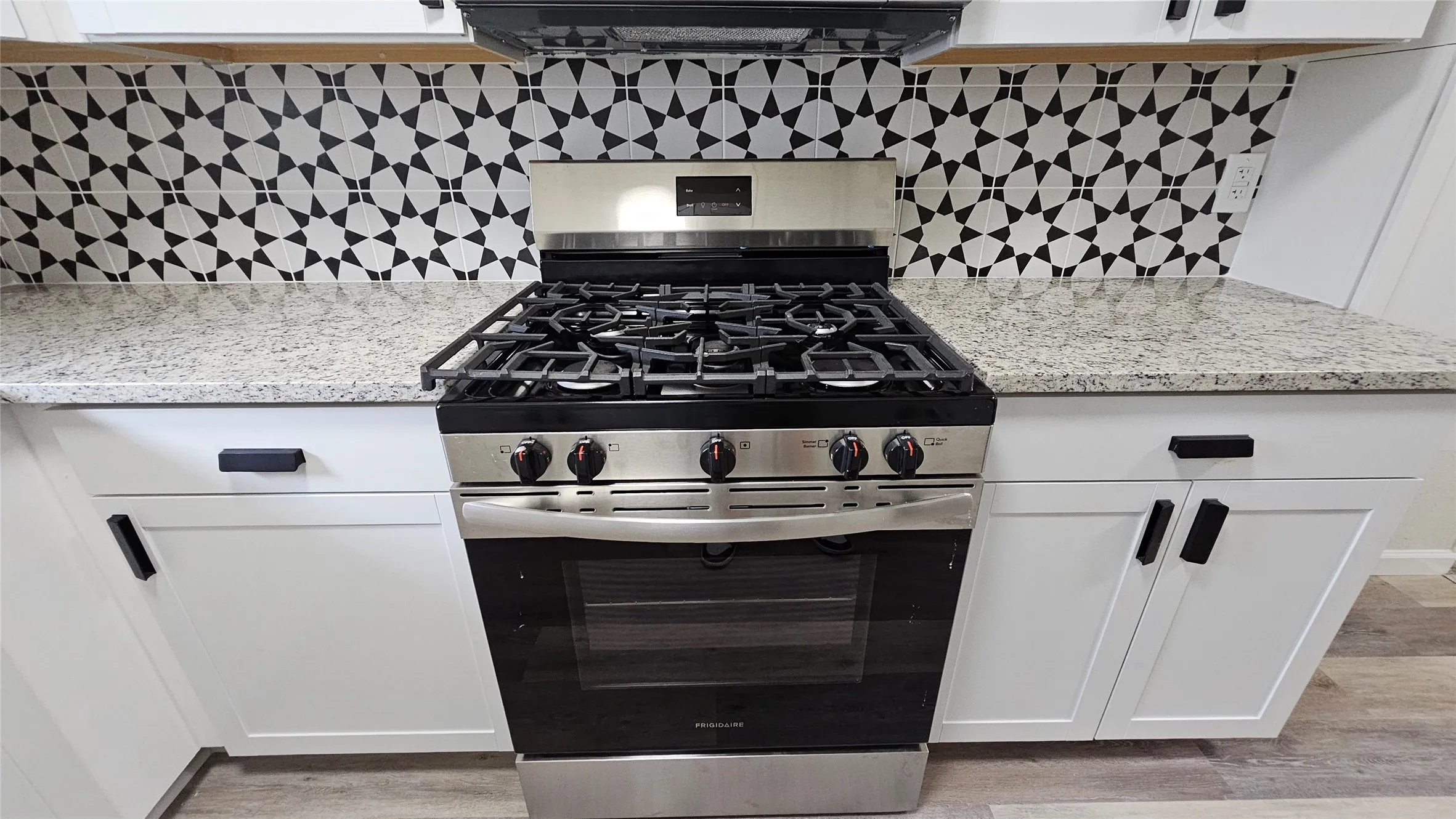 Kitchen featuring stainless steel range with gas stovetop, range hood, light wood-type flooring, and white cabinetry